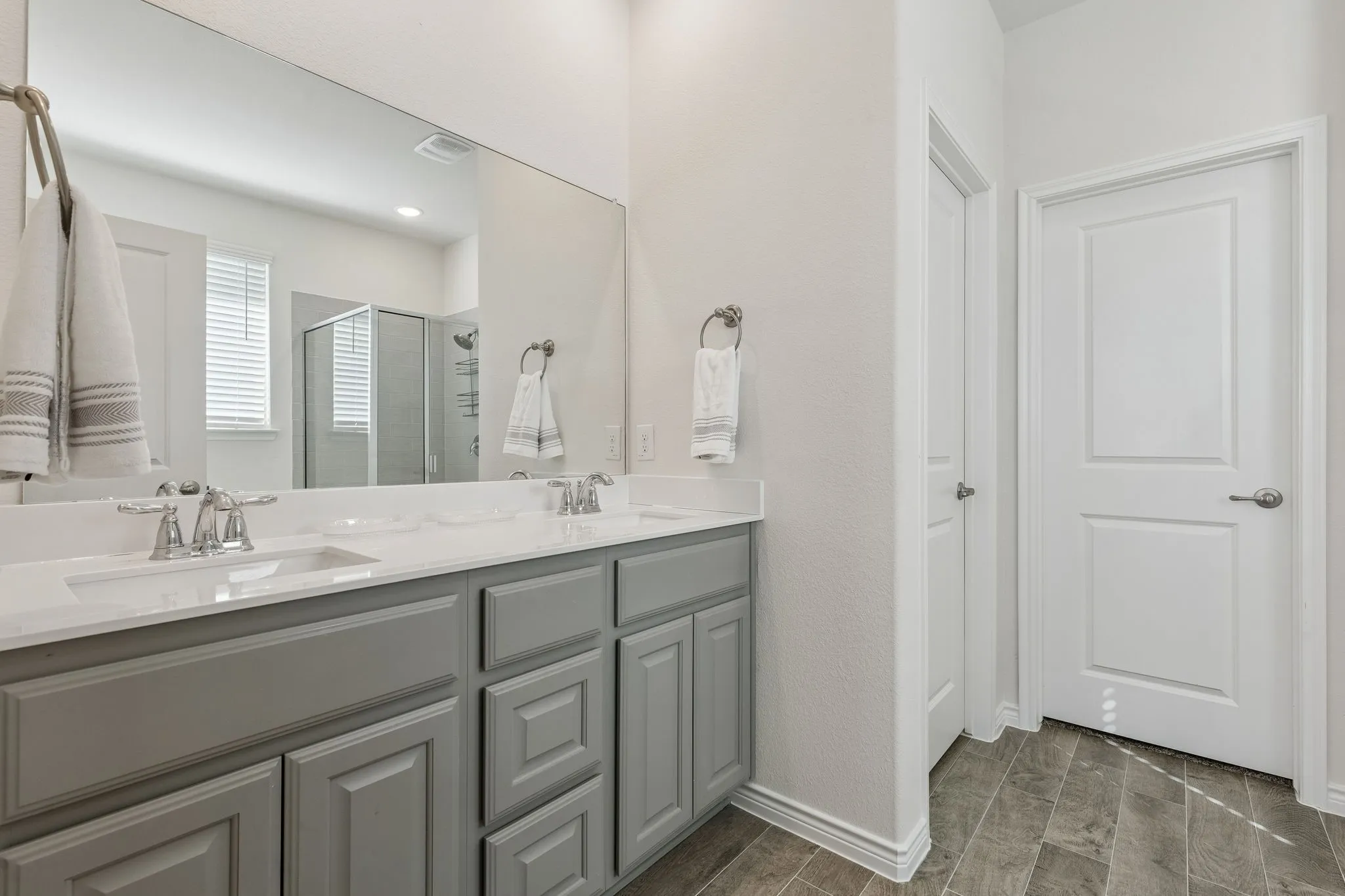 Full bath featuring double vanity, a shower stall, and wood tiled floors
