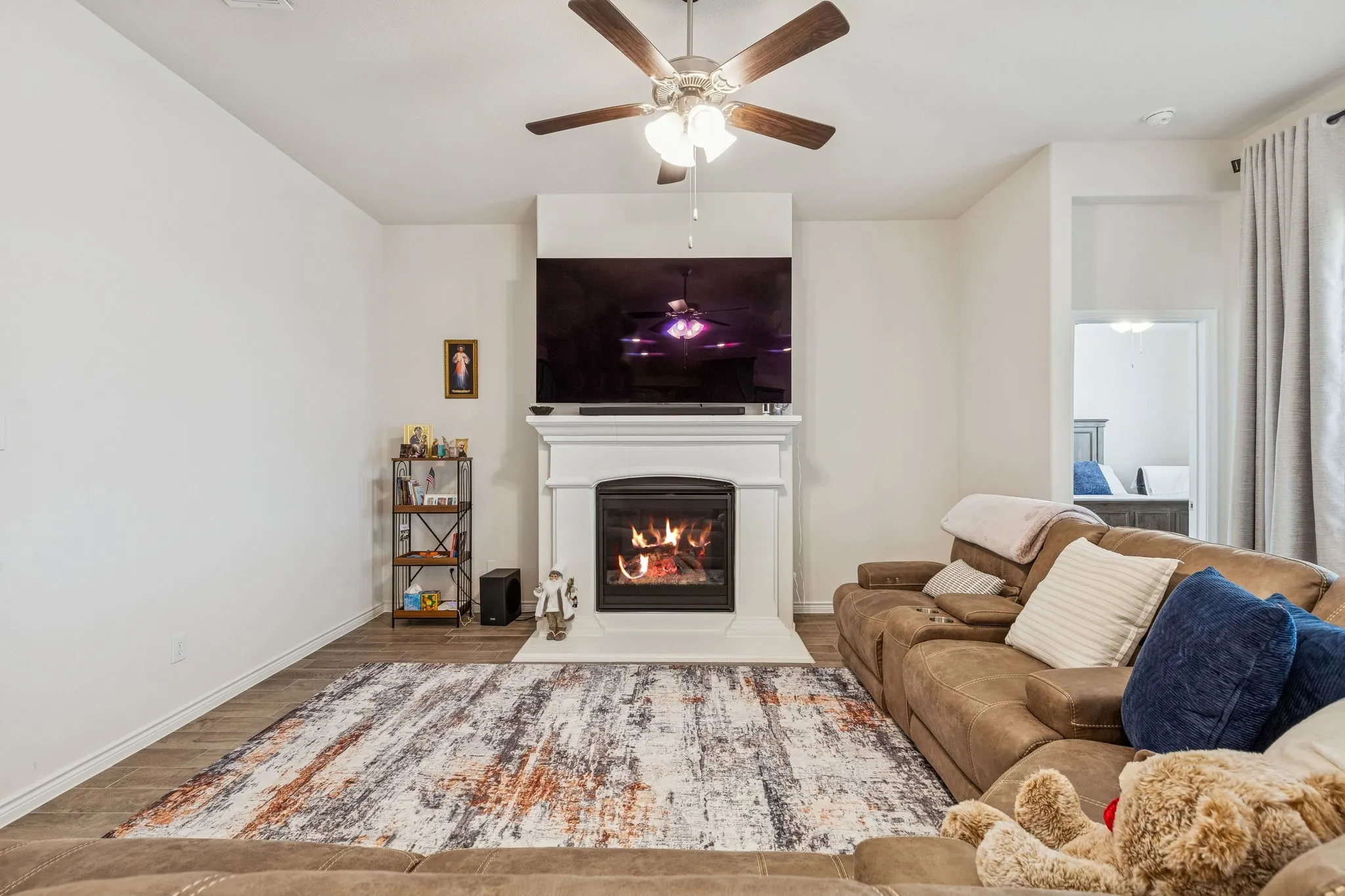 Living room featuring a lit fireplace, wood finished floors, and ceiling fan