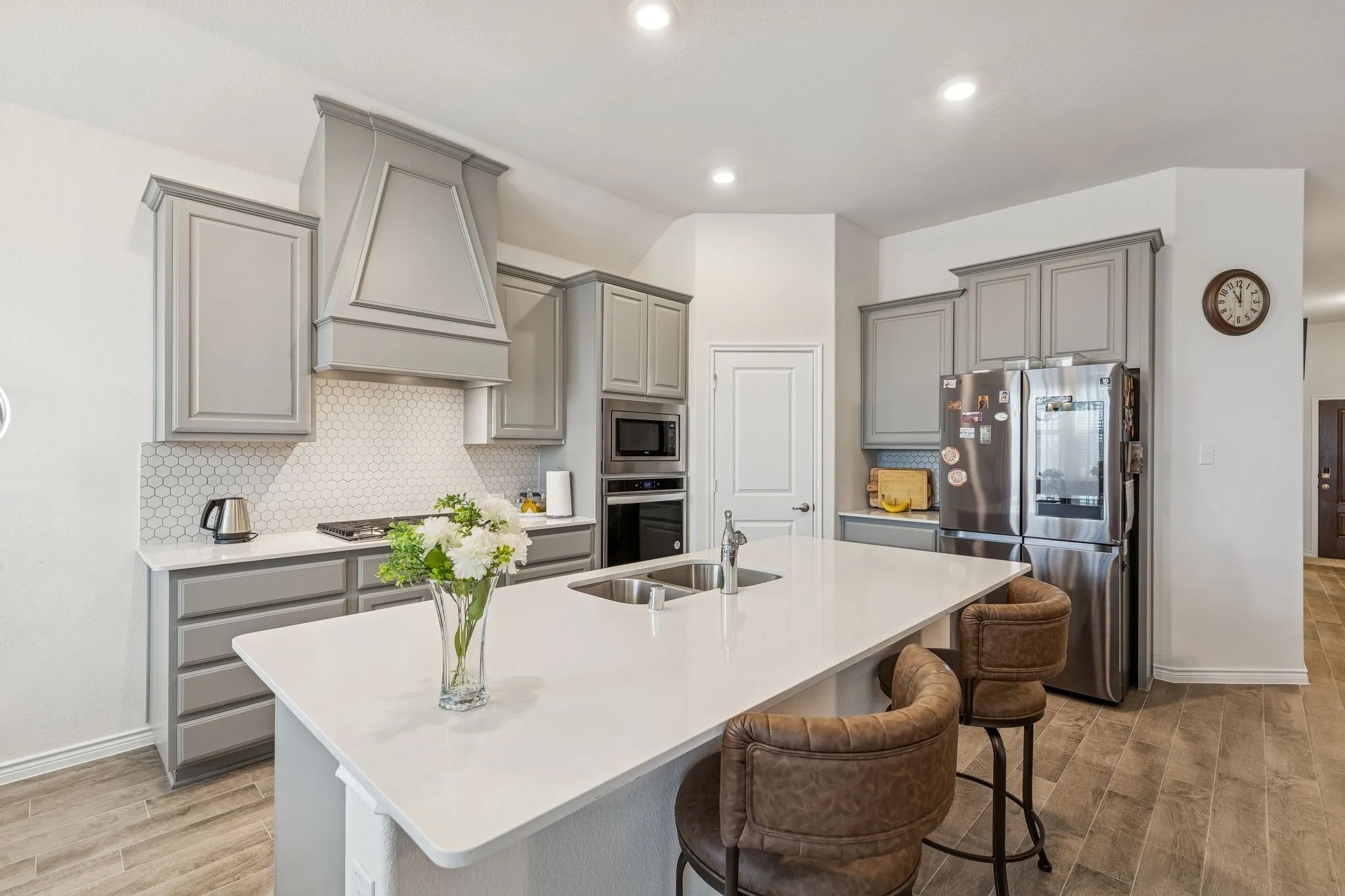 Kitchen featuring gray cabinets, stainless steel appliances, tasteful backsplash, light wood-type flooring, and recessed lighting