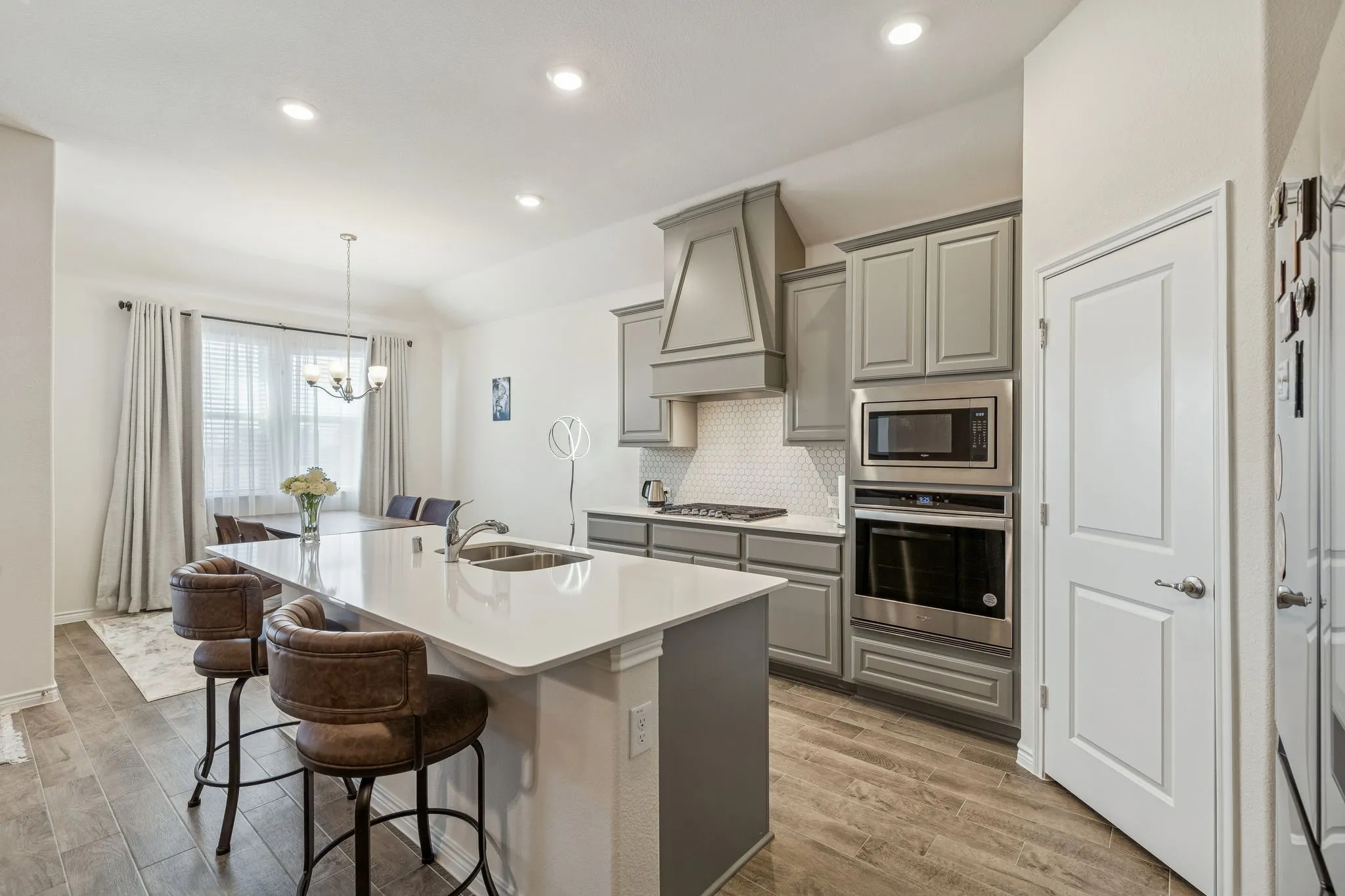 Kitchen featuring gray cabinets, stainless steel appliances, a chandelier, backsplash, and a breakfast bar area