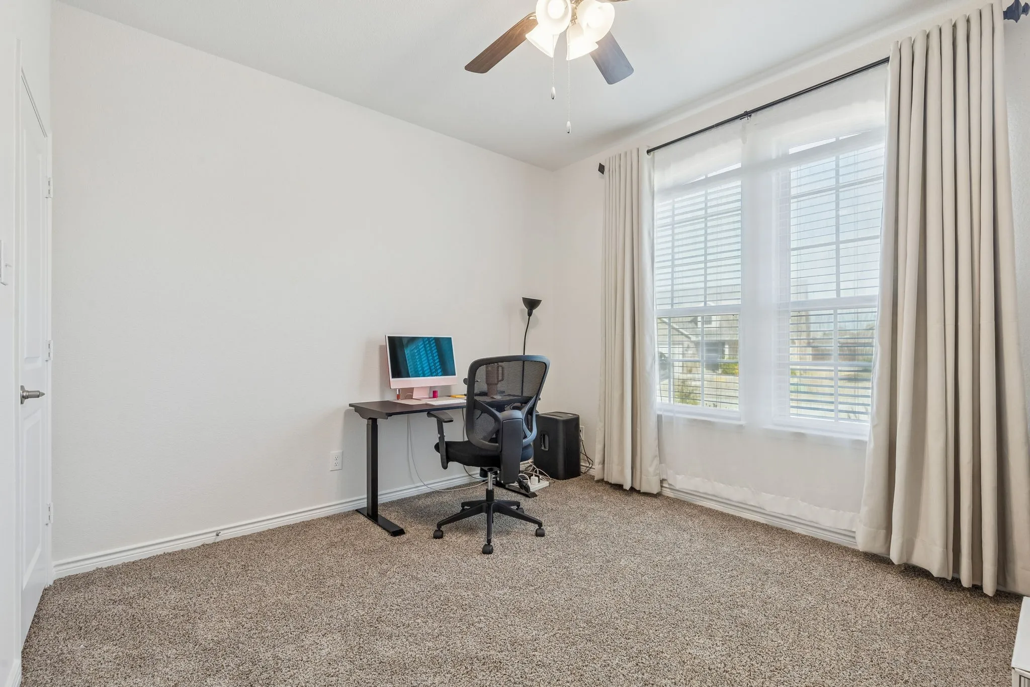Carpeted home office with ceiling fan and baseboards