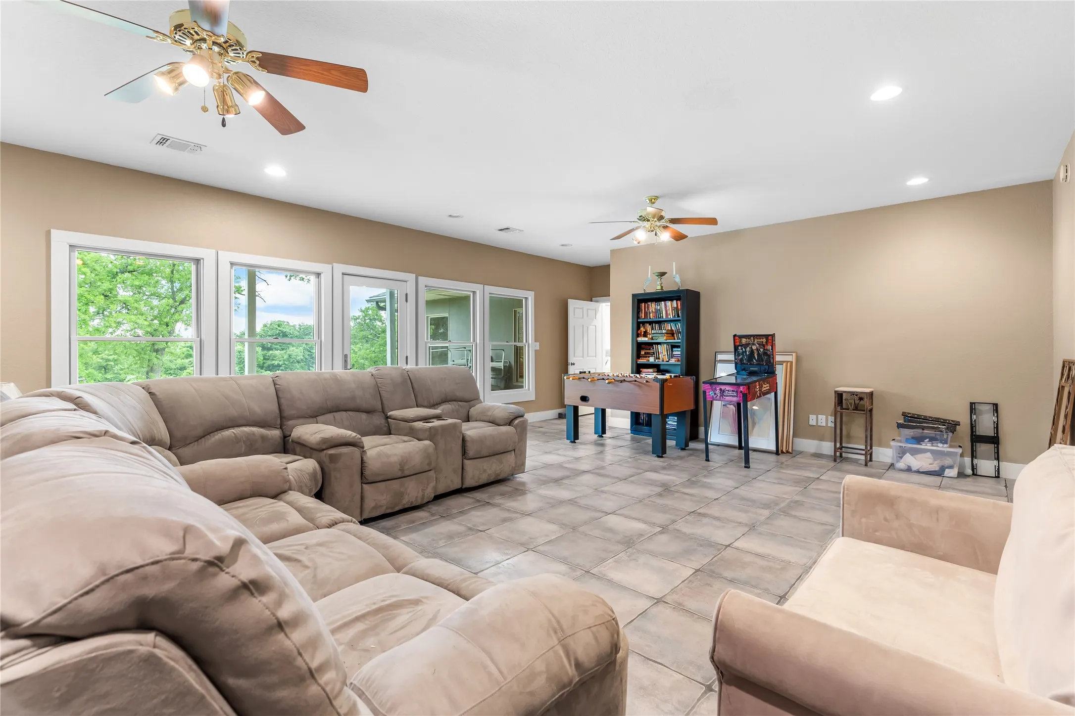 Expansive recreation room featuring tile flooring, recessed lighting, and multiple windows providing views of the outdoors