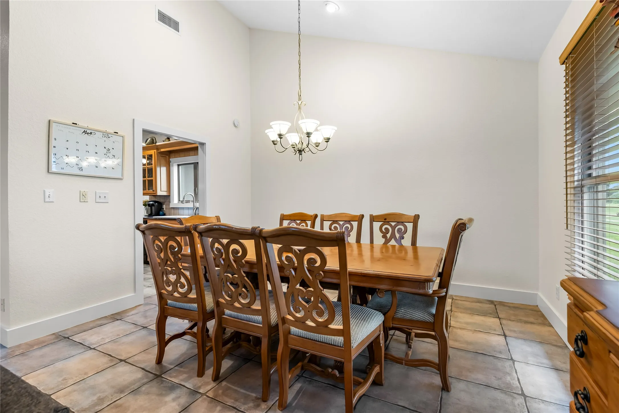 Dining area featuring a vaulted ceiling, a chandelier, and tile flooring