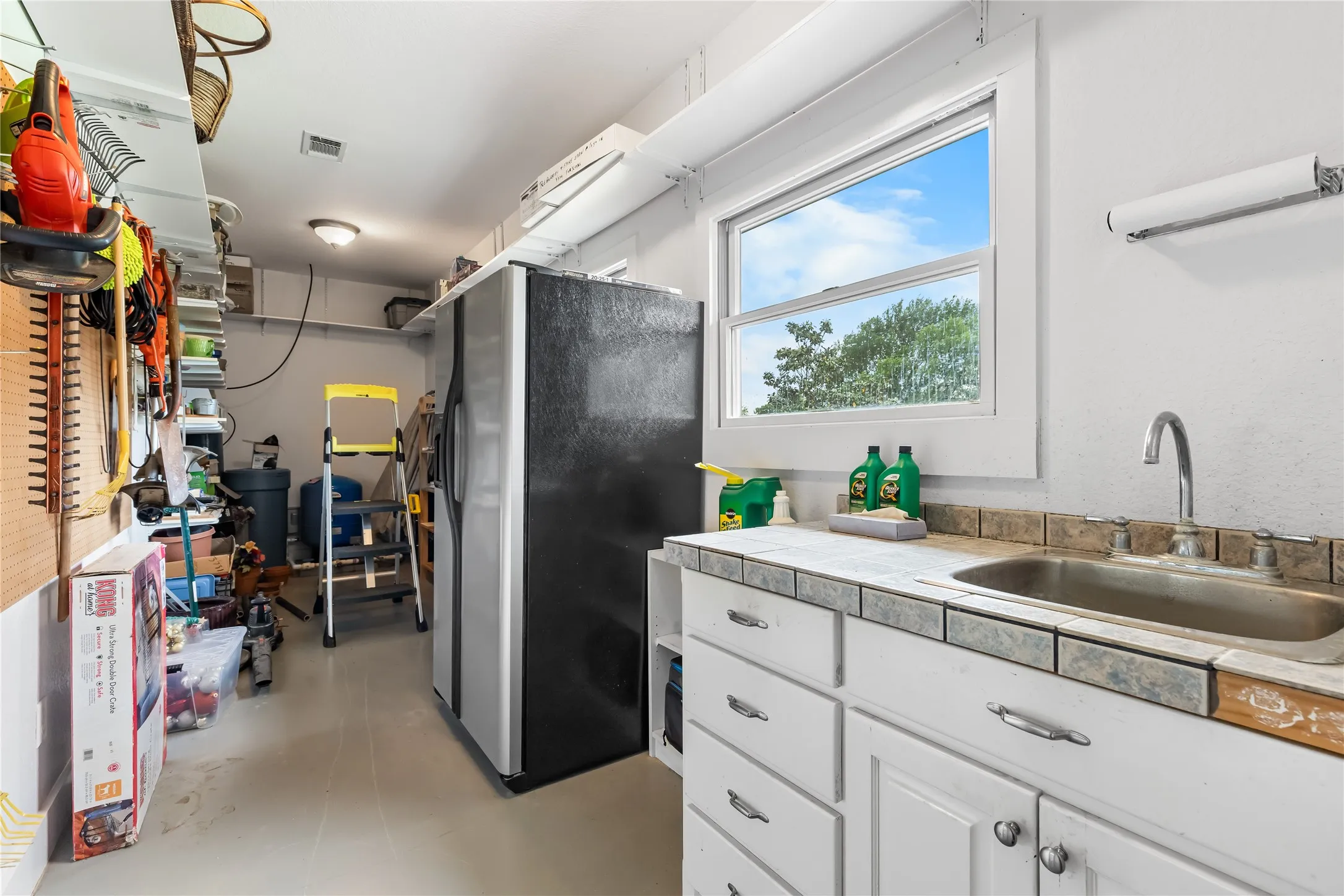The property includes a workshop area off garage with entrance from garage or home with a window, a sink with a faucet, and white cabinetry