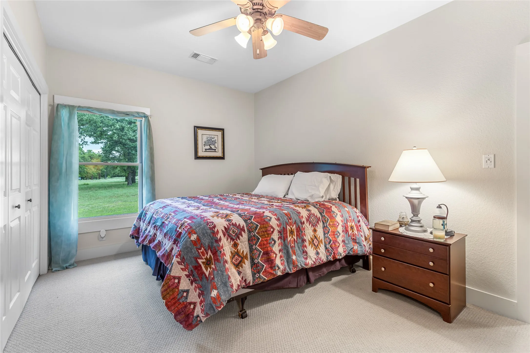 The property features an interior space with light-colored carpeted flooring, a window offering views of green landscaping, and white walls