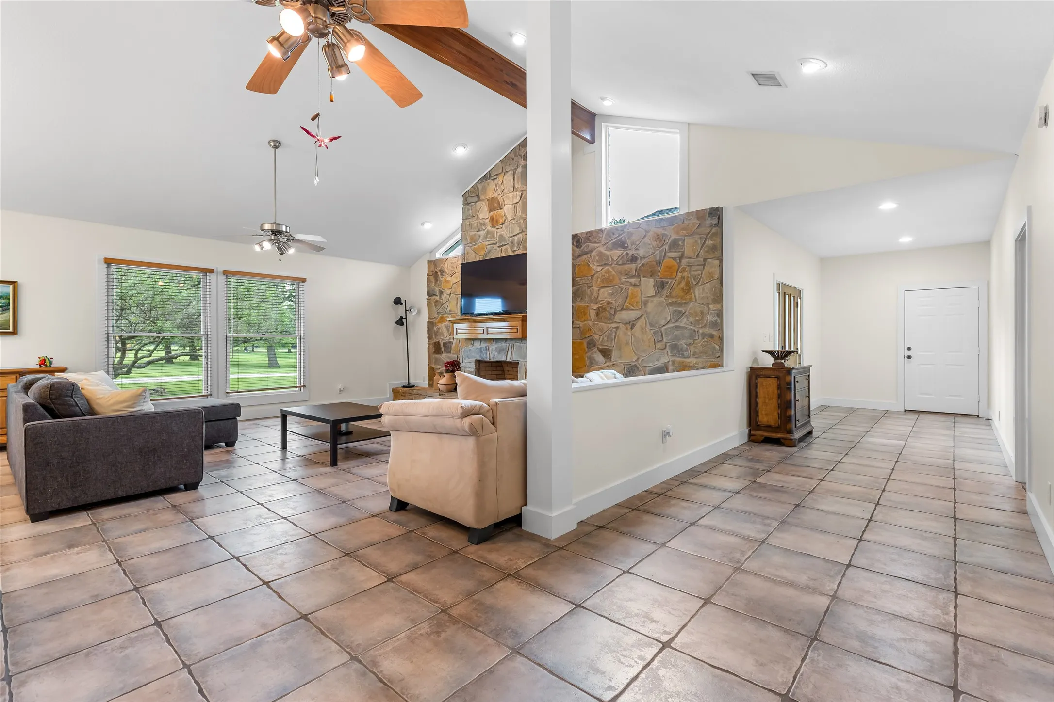 The living area features a vaulted ceiling with exposed wooden beams, recessed lighting, and a ceiling fan
