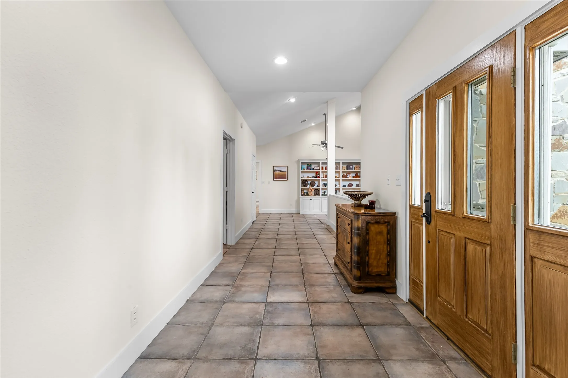Entryway featuring a large wooden door with glass panels, stone wall accents, and light-colored tile flooring