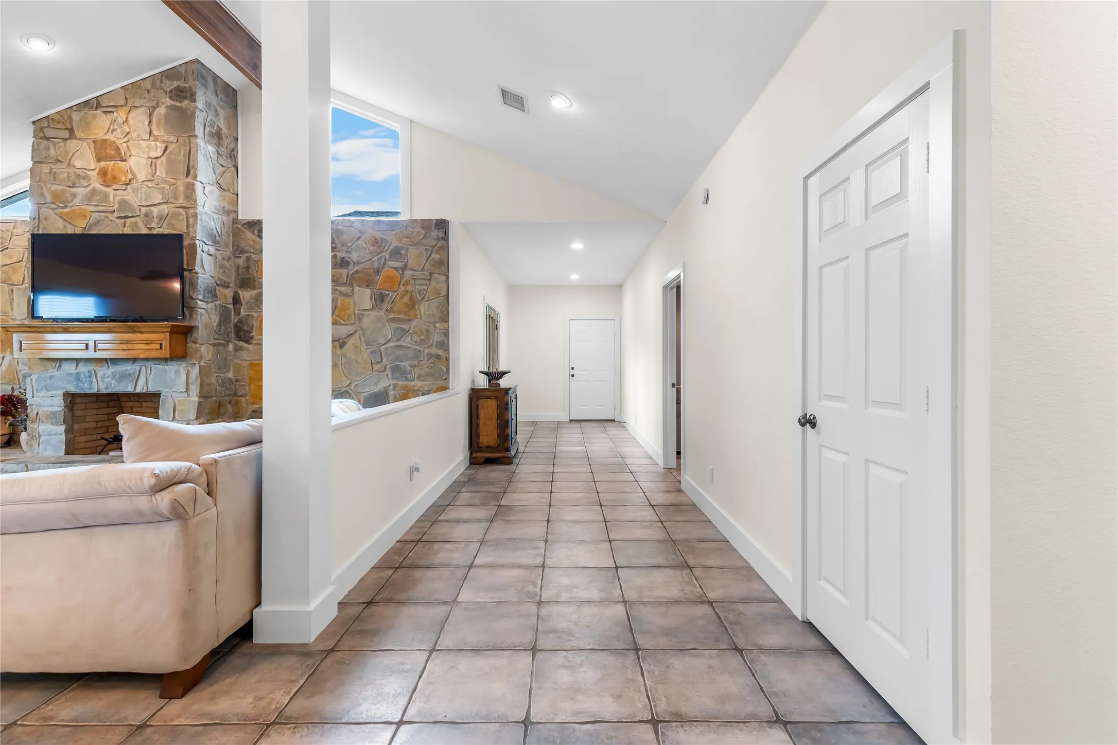 The property features a bright hallway with tiled floors and white walls, leading to several white paneled doors