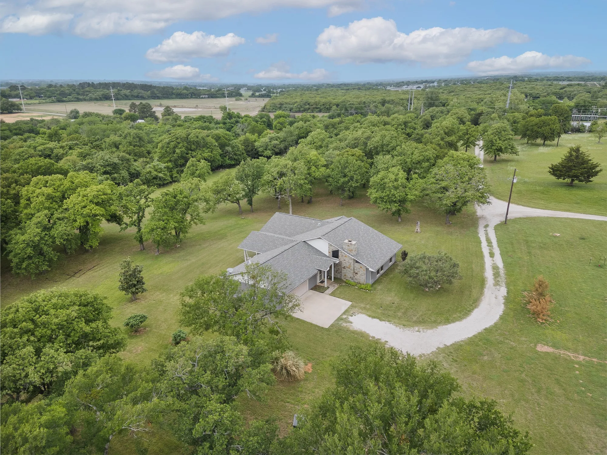 The property features a spacious yard with mature trees and a gravel driveway