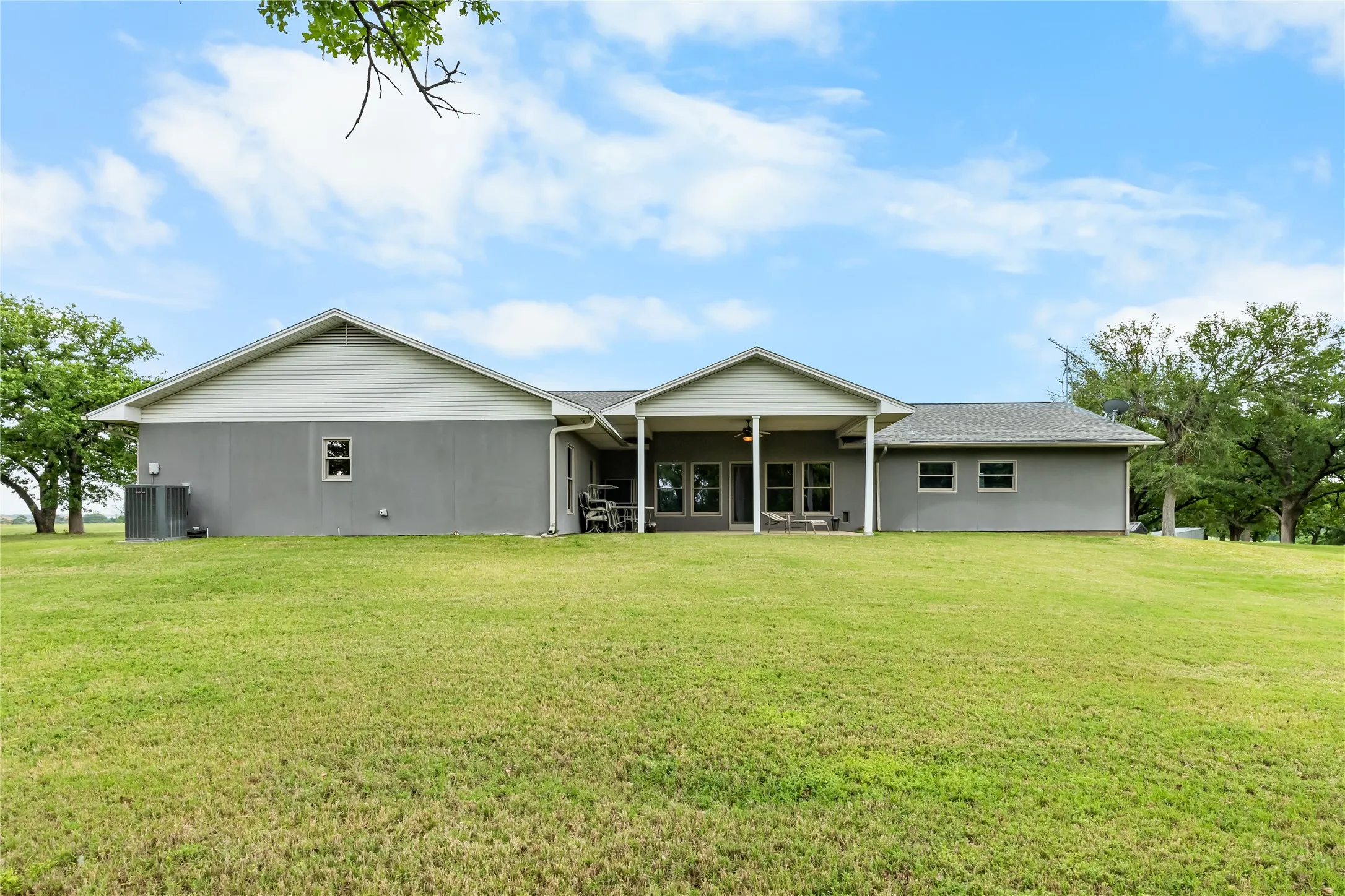The property features a grey exterior, a covered patio, and a well-maintained lawn
