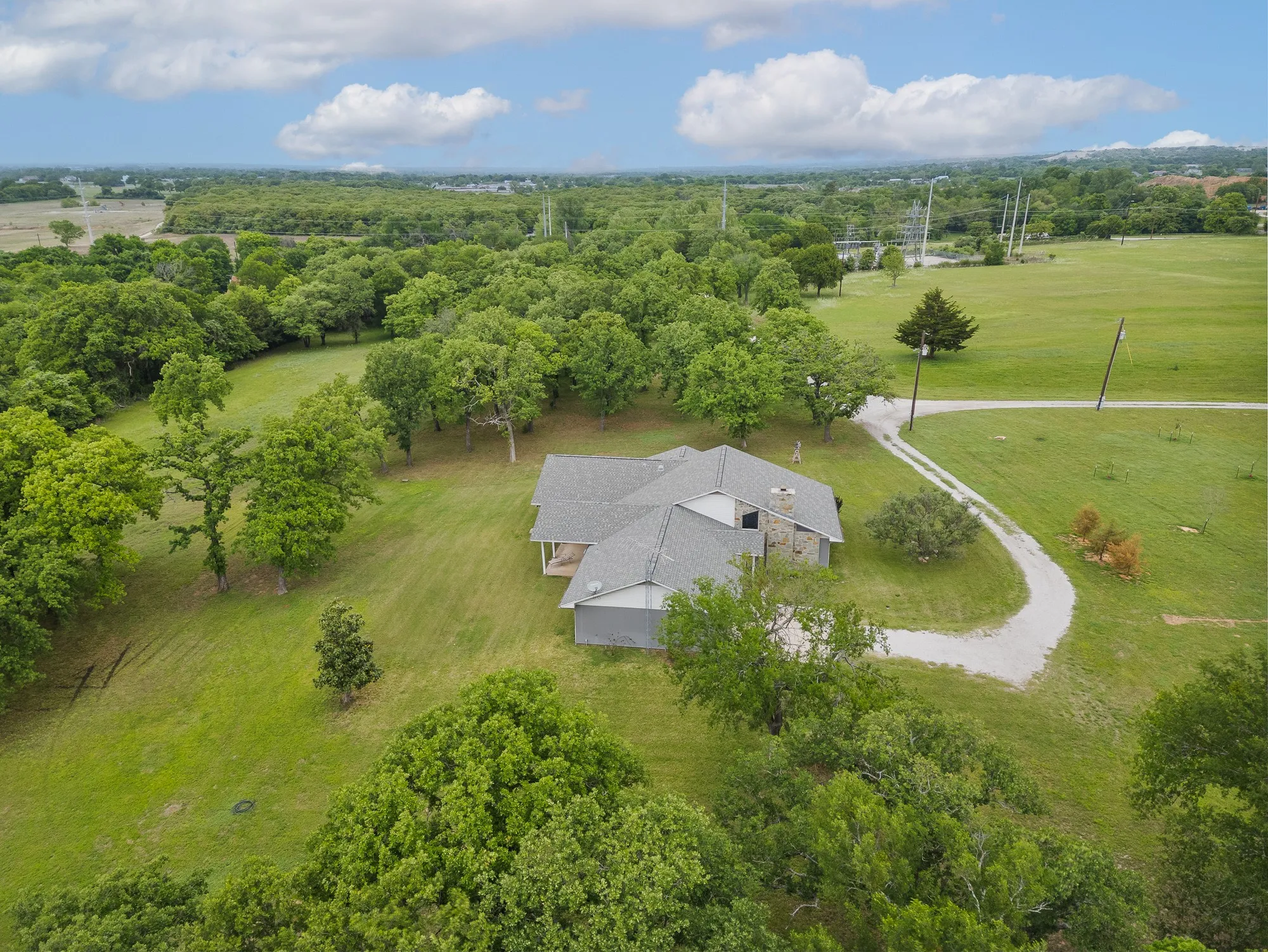 The property is situated amidst extensive green space with a gravel driveway leading to the residence