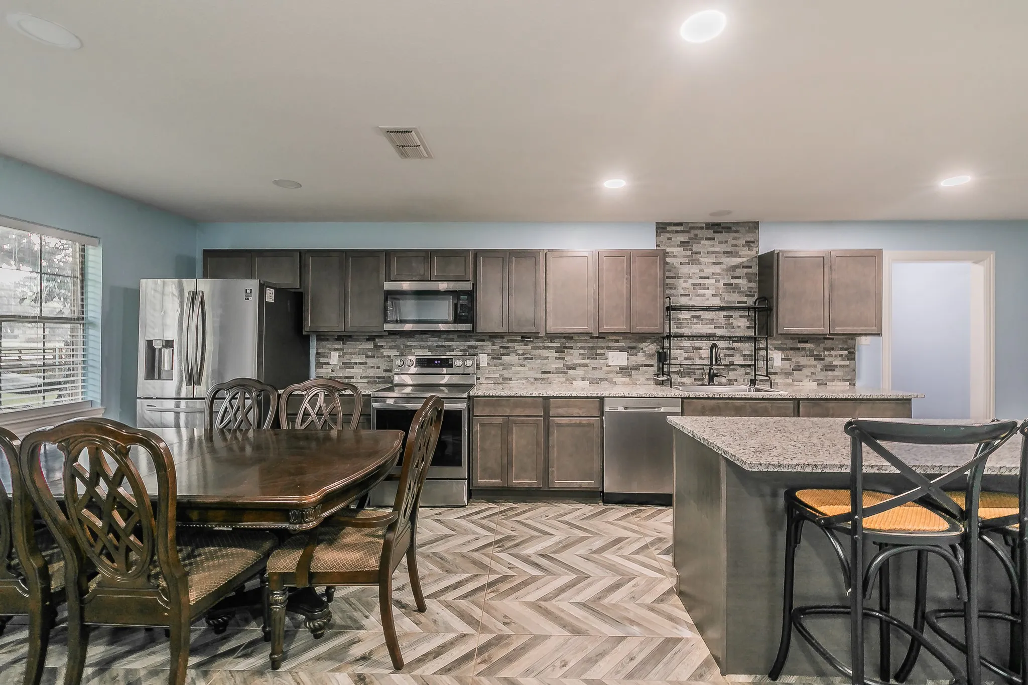 Kitchen with stainless steel appliances, backsplash, recessed lighting, a breakfast bar area, and dark brown cabinetry