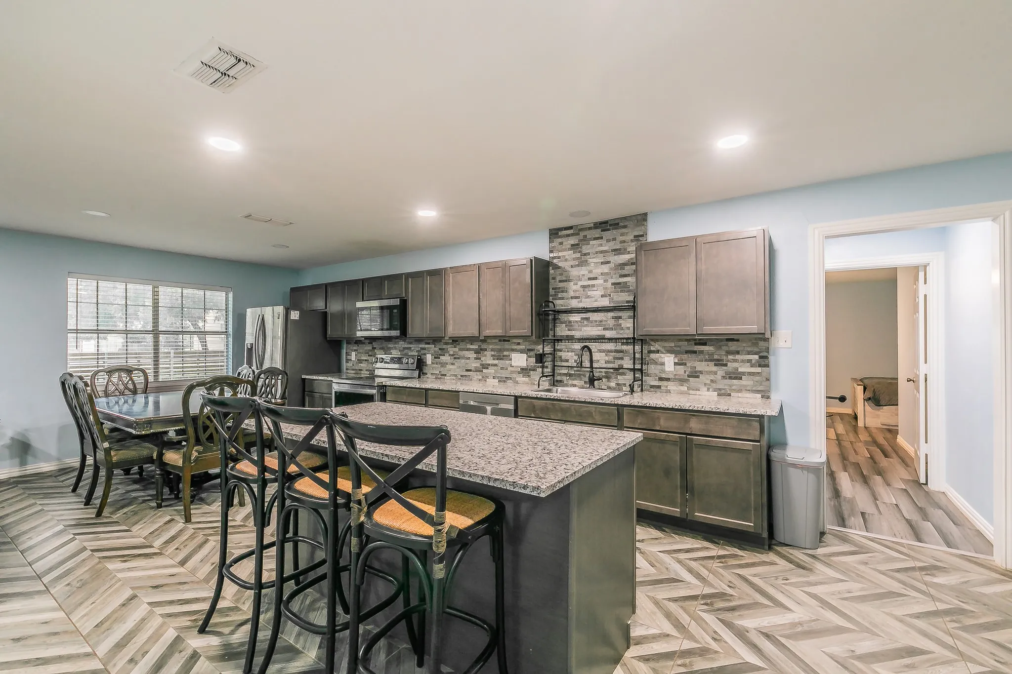 Kitchen featuring a breakfast bar area, stainless steel appliances, tasteful backsplash, a kitchen island, and light stone counters
