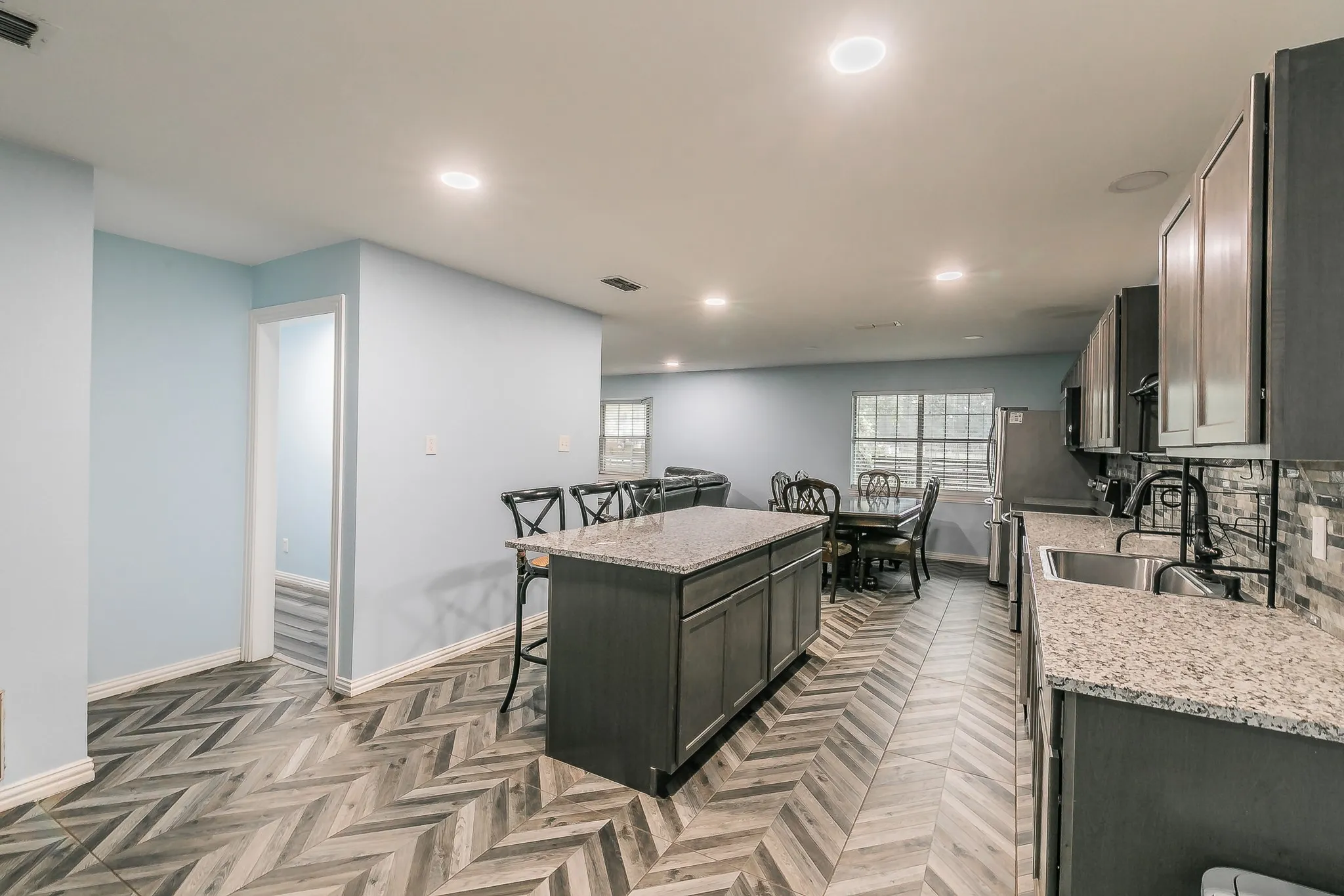 Kitchen with a center island, a kitchen breakfast bar, recessed lighting, light stone counters, and tasteful backsplash