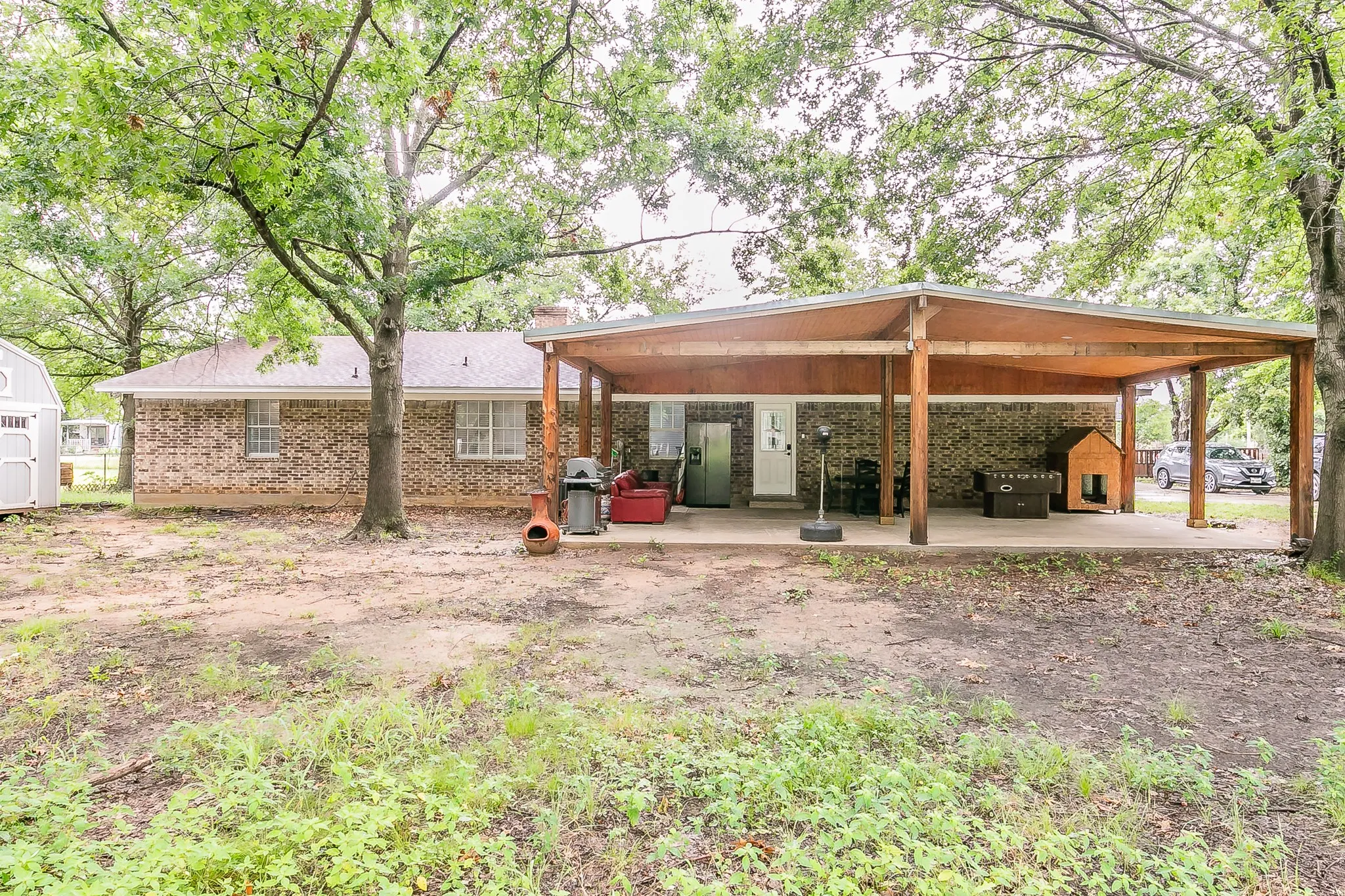 Rear view of house with a storage unit, brick siding, and a carport