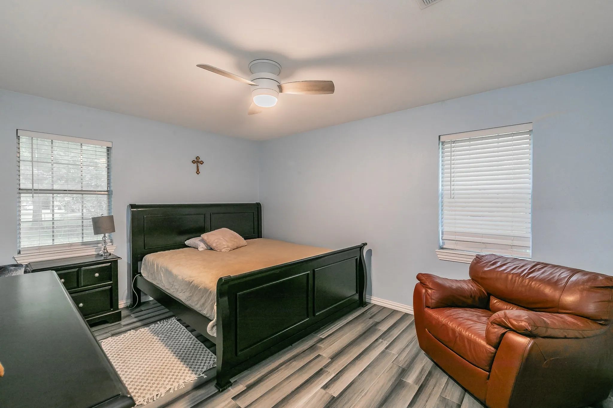 Bedroom with light wood-style flooring, multiple windows, and a ceiling fan