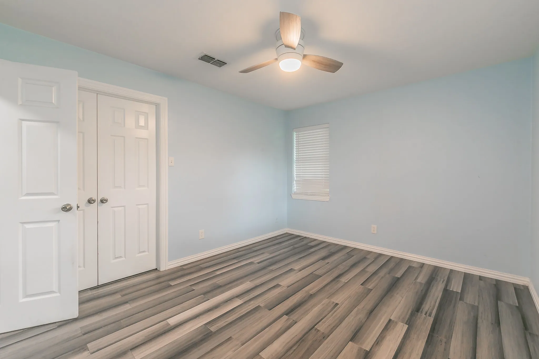 Unfurnished bedroom featuring wood finished floors, a closet, and ceiling fan