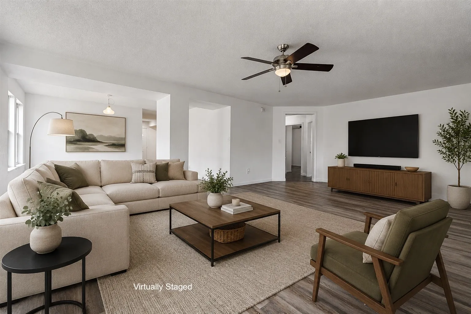 Open-concept living space featuring wood-finish flooring, white walls, and a ceiling fan with integrated lighting