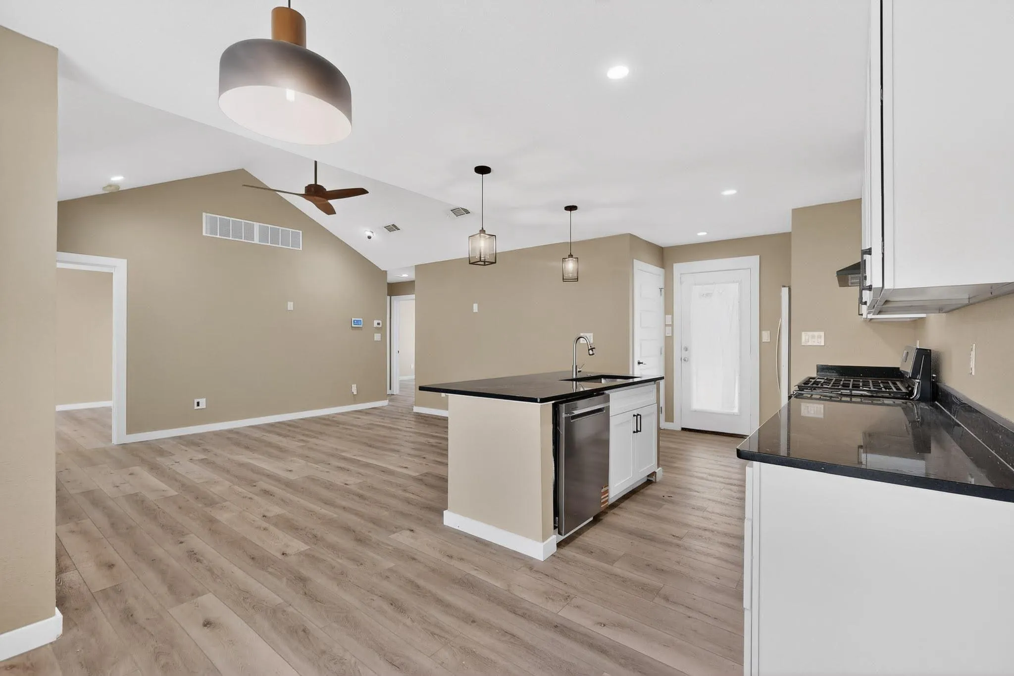 Kitchen with a center island with sink, white cabinets, open floor plan, light wood-style flooring, and hanging light fixtures