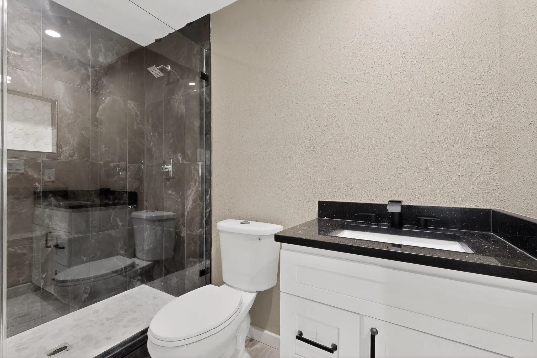 Bathroom with vanity, a textured wall, and a stall shower