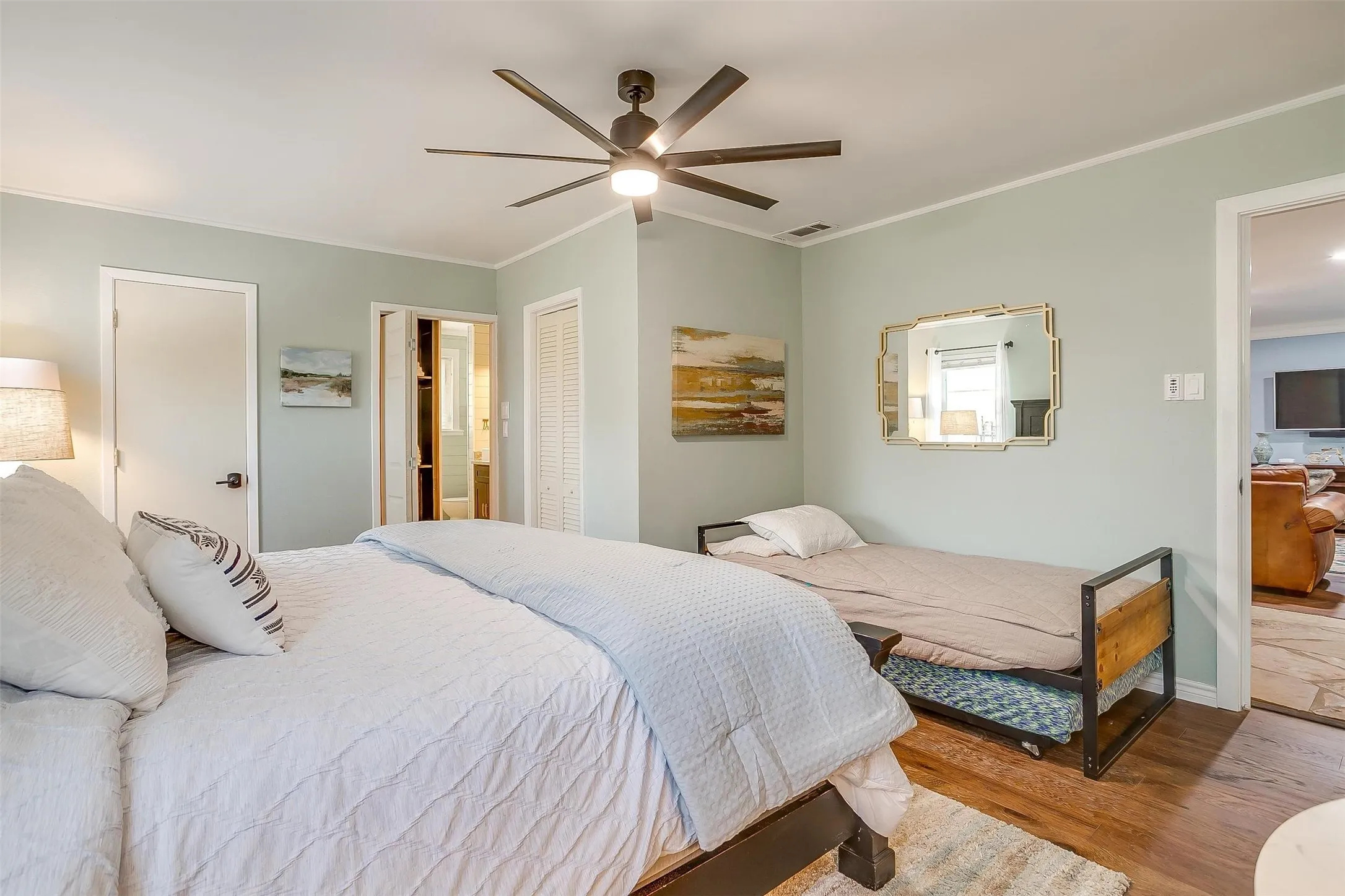 Bedroom with crown molding, a closet, wood finished floors, a ceiling fan, and connected bathroom