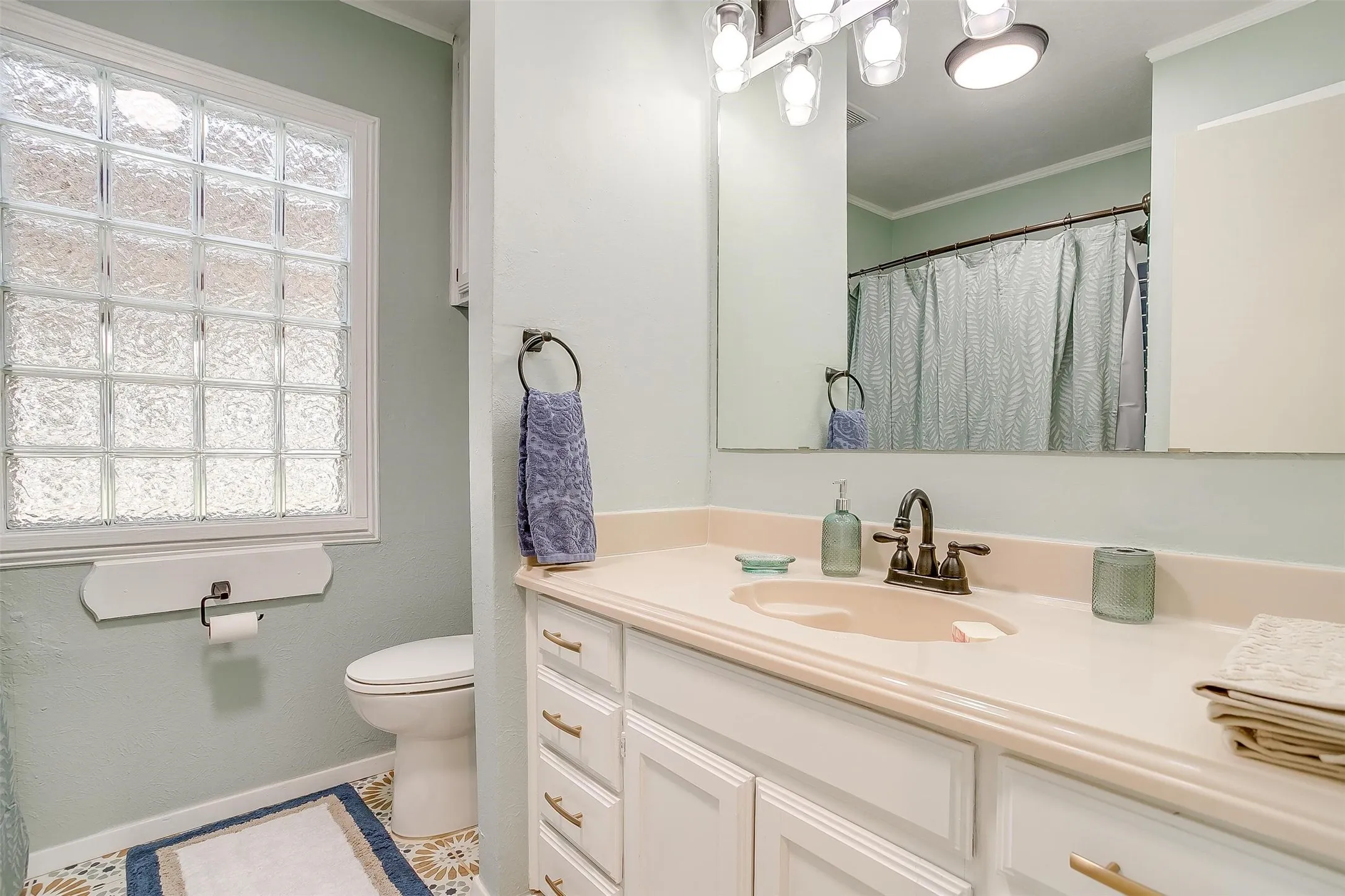 Full bath with vanity, ornamental molding, and curtained shower