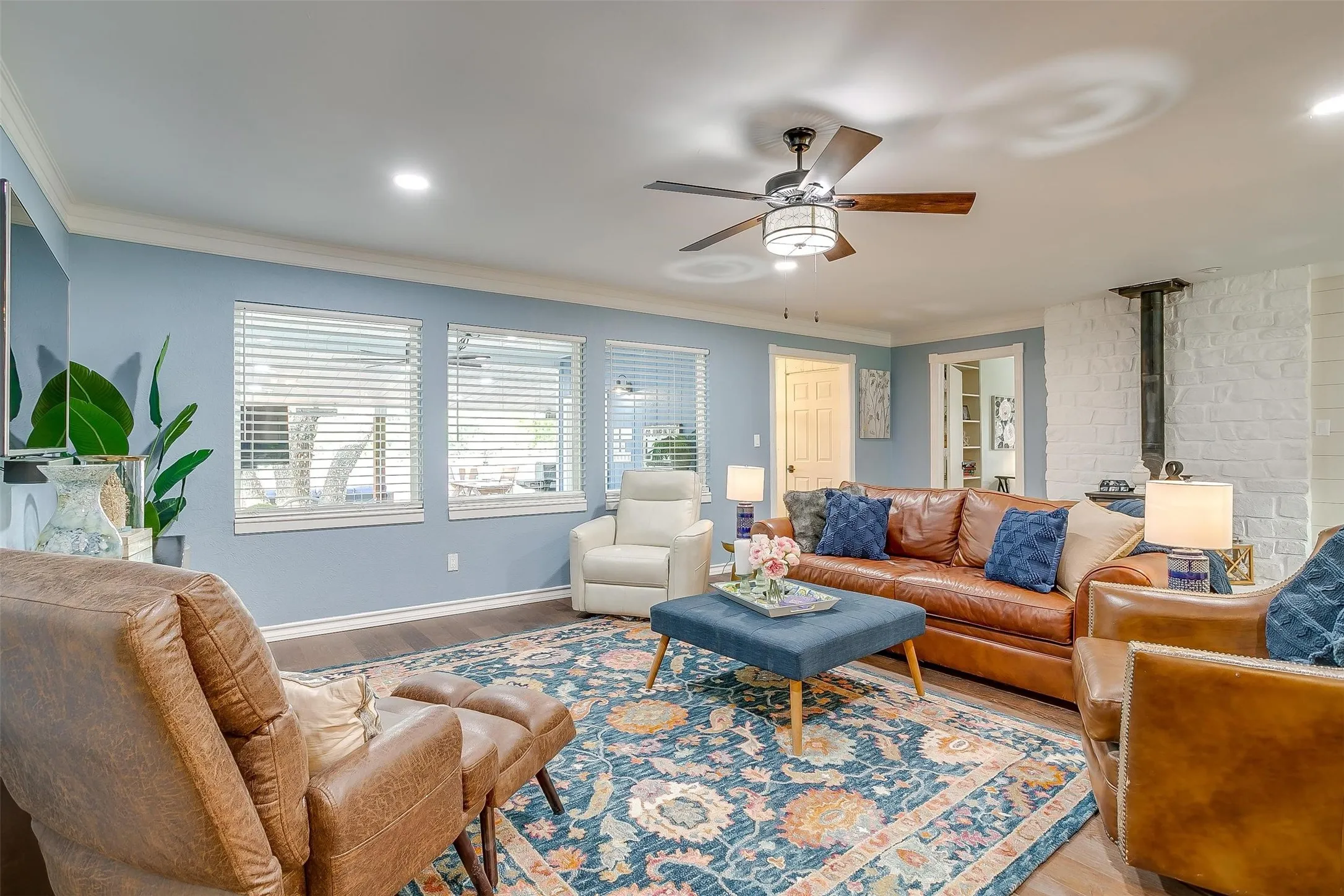 Living room featuring crown molding, a ceiling fan, wood finished floors, a wood stove, and recessed lighting