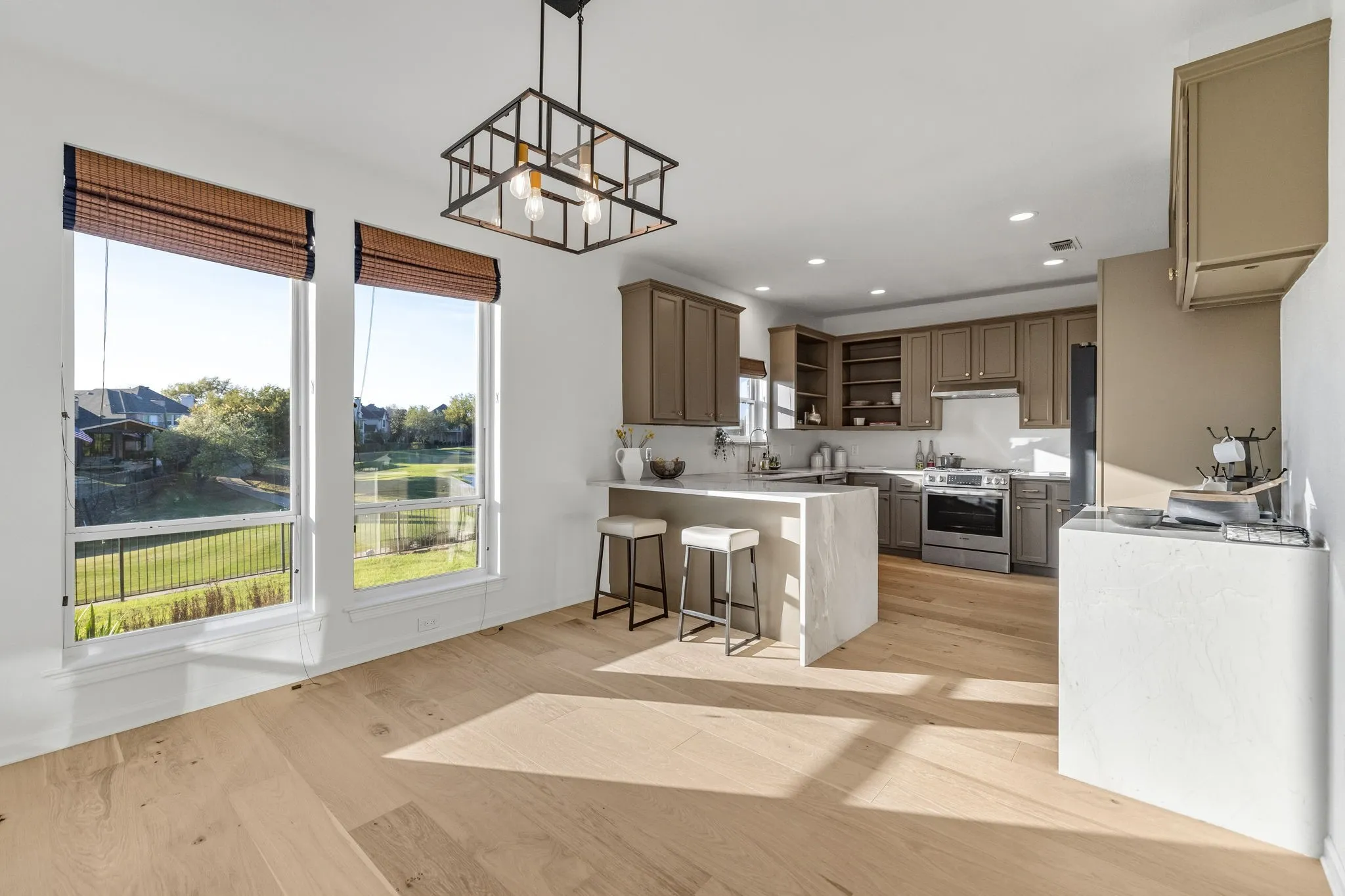 Kitchen with open shelves, a peninsula, a breakfast bar area, stainless steel appliances, and suspended lighting