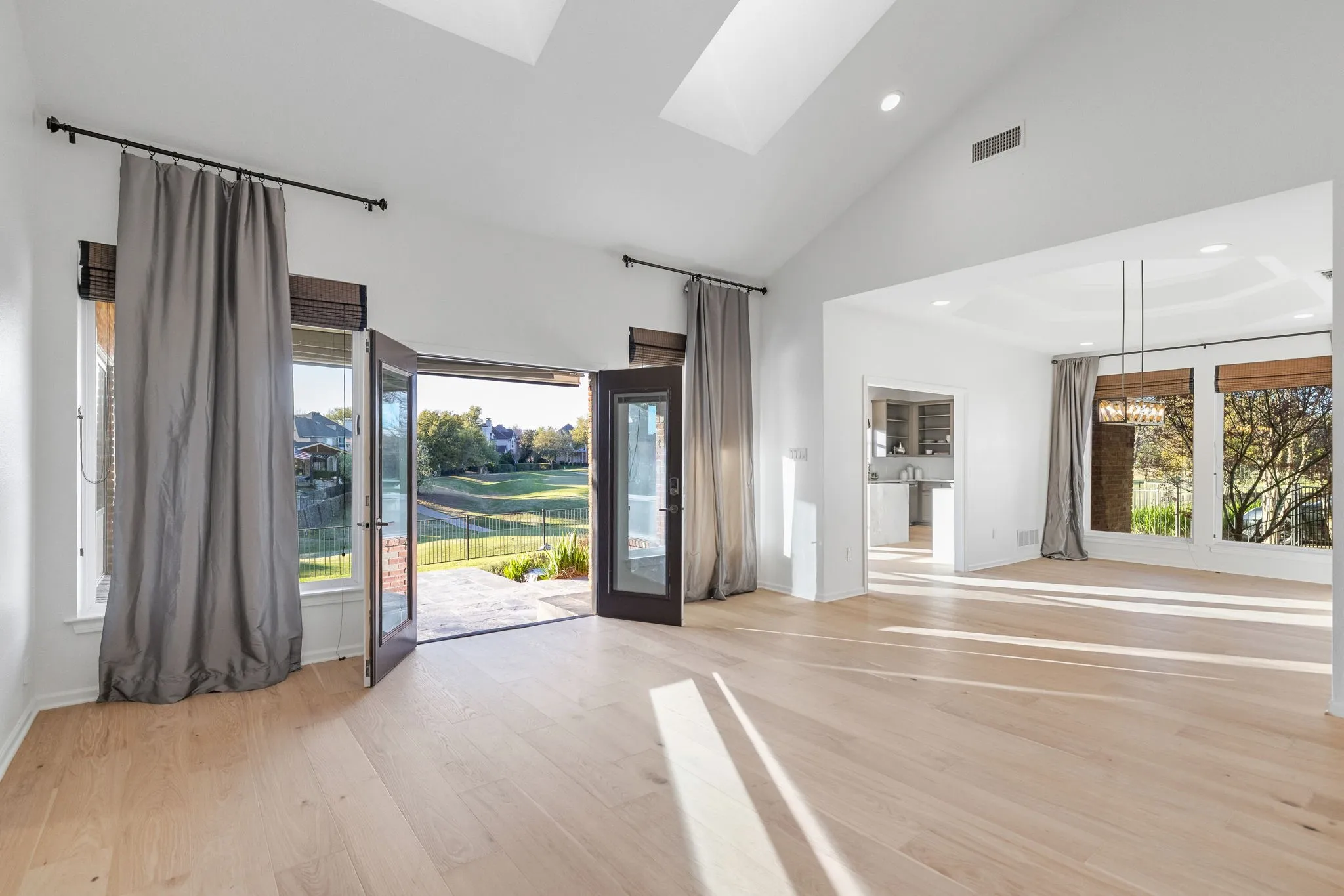 Spare room featuring a skylight, light wood-style flooring, vaulted ceiling, and hanging lights