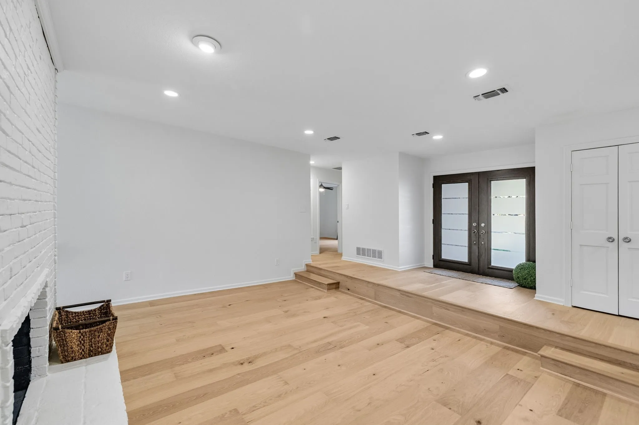 Entryway featuring french doors, light wood-style floors, recessed lighting, and a fireplace