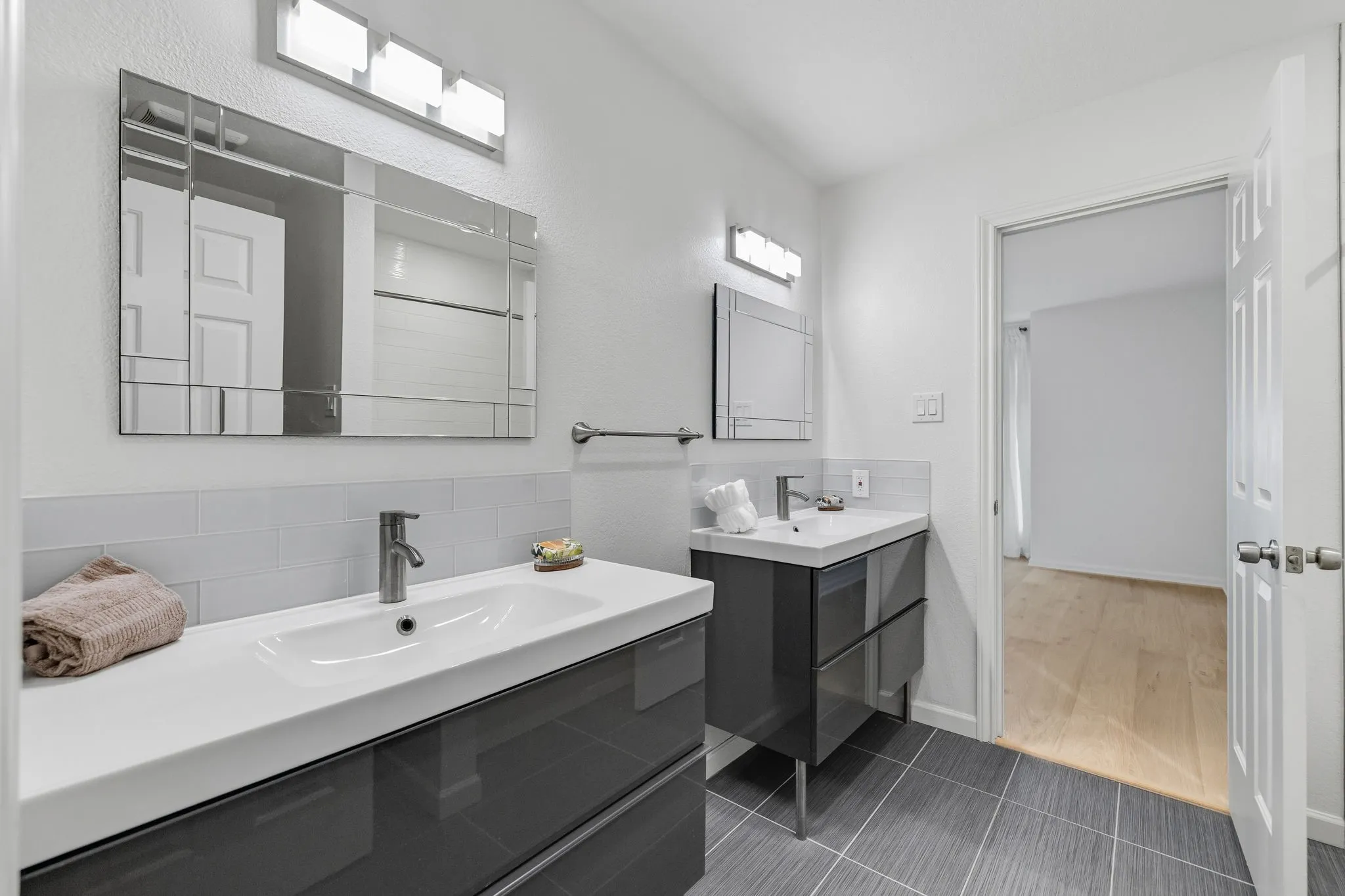 Full bath with two vanities and dark tile patterned flooring