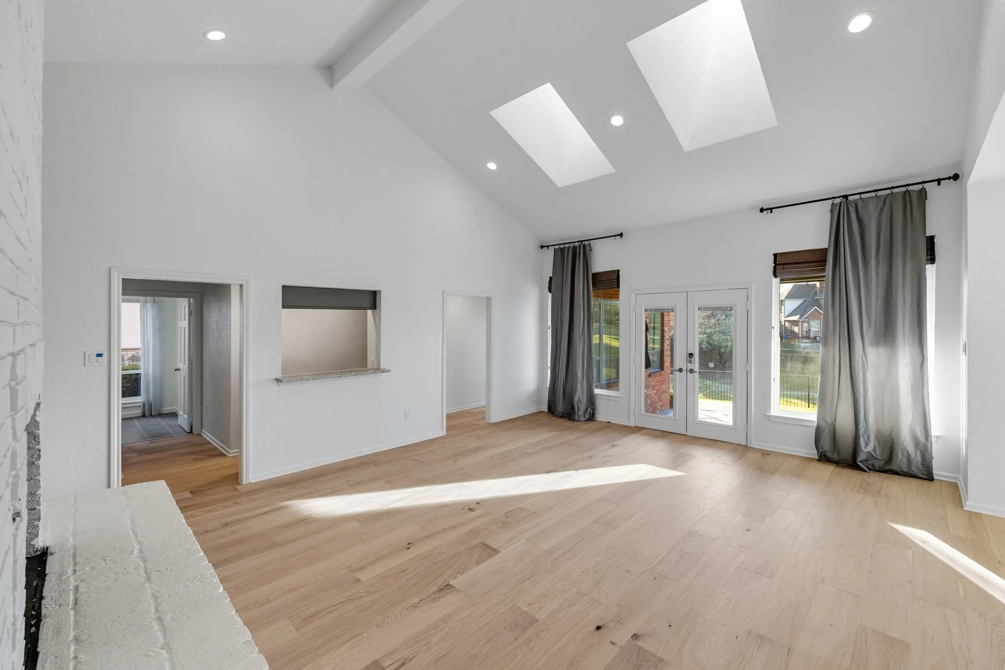 Unfurnished living room with light wood-type flooring, french doors, a skylight, healthy amount of natural light, and recessed lighting