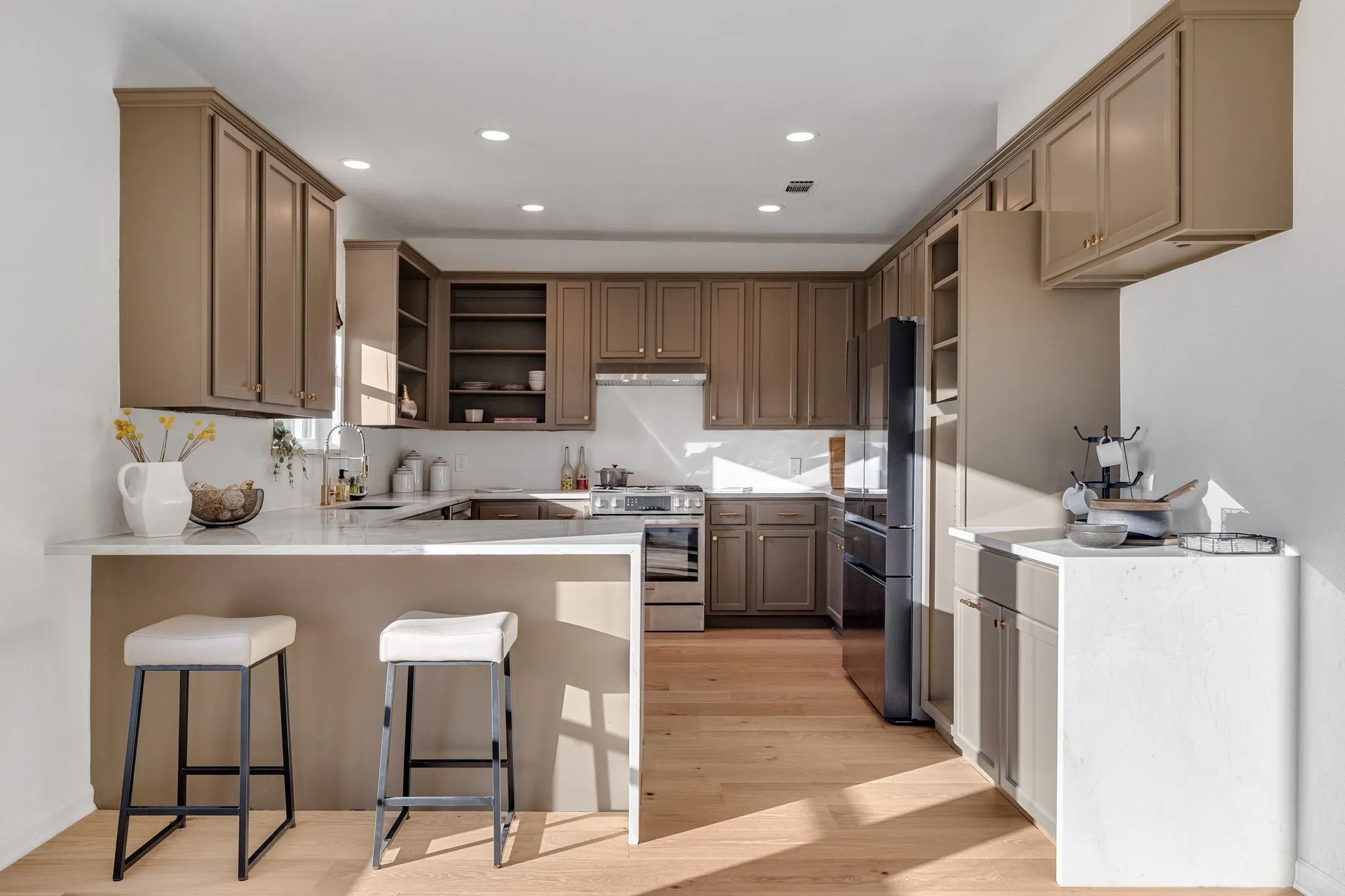 Kitchen featuring open shelves, a peninsula, stainless steel stove, a kitchen bar, and recessed lighting