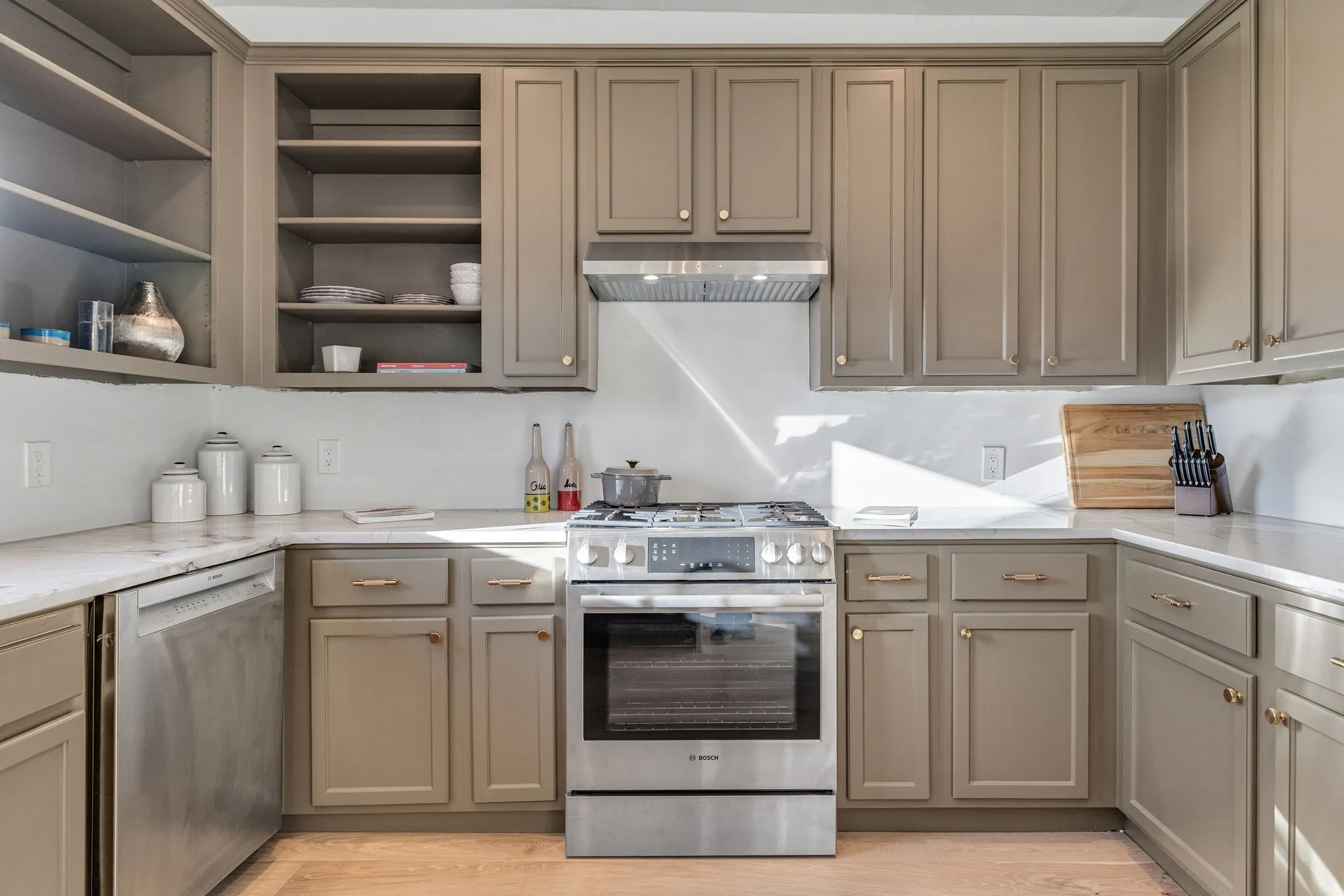 Kitchen with stainless steel appliances, range hood, gray cabinets, and light wood-type flooring