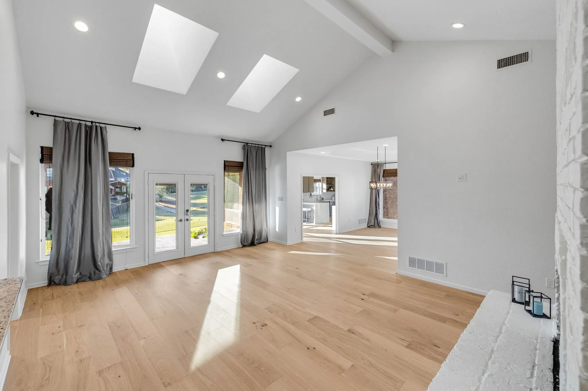 Unfurnished living room featuring french doors, a skylight, light wood finished floors, and suspended lighting