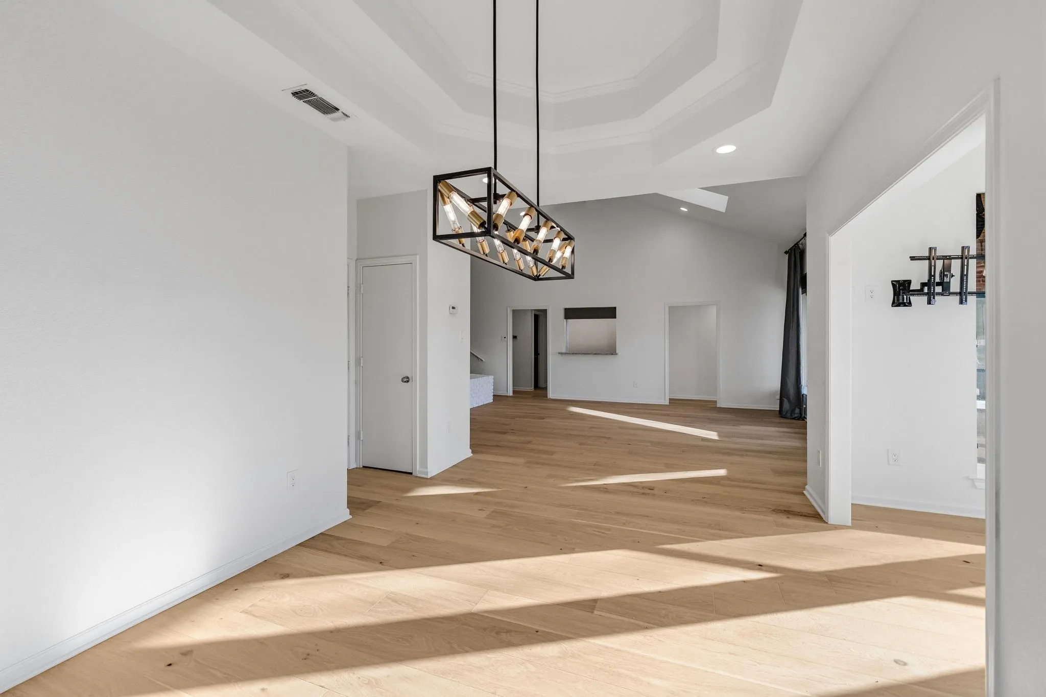 Unfurnished dining area with suspended lighting, light wood finished floors, and a high ceiling