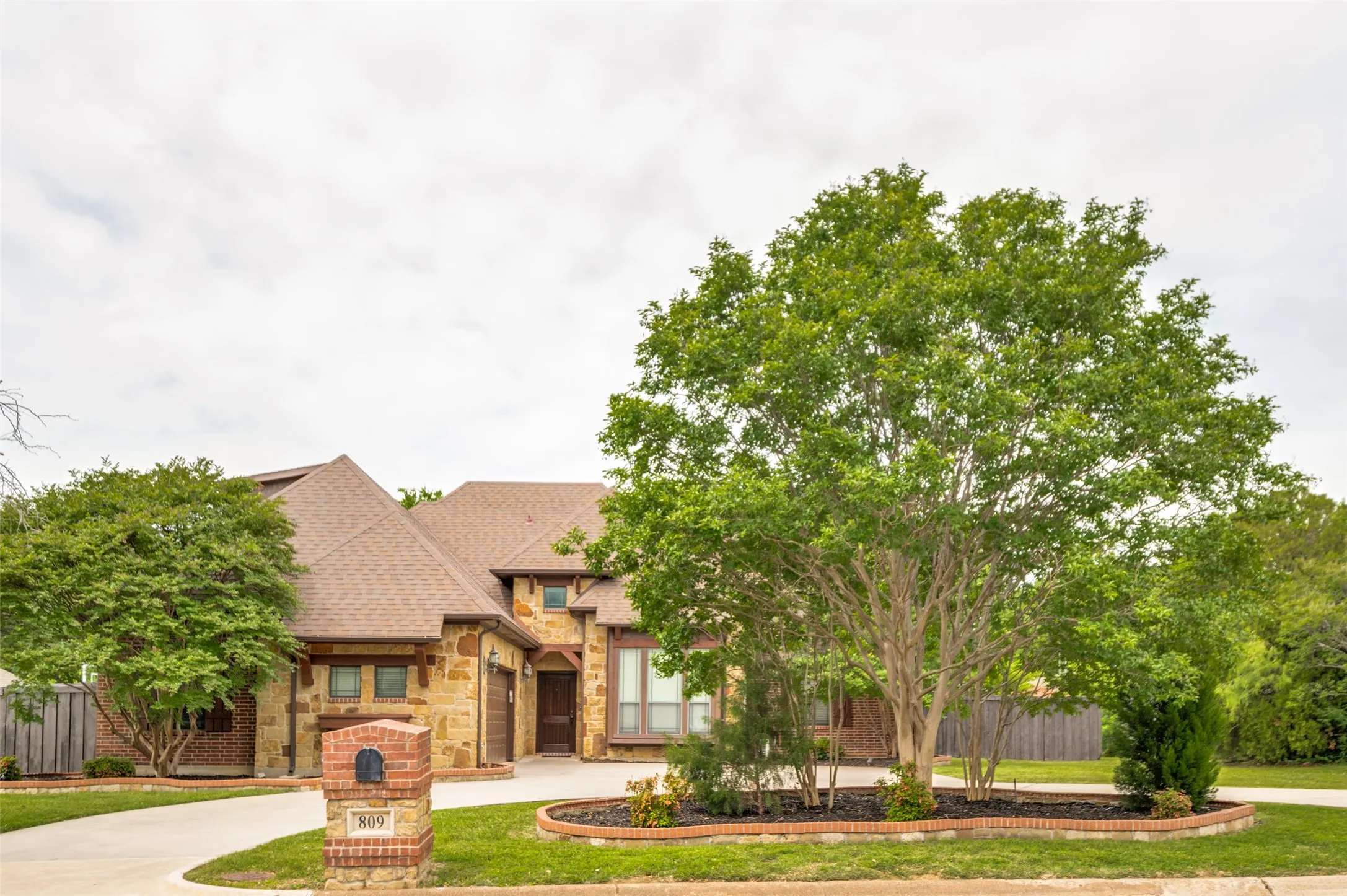 Stone facade residence featuring a prominent front entrance, an integrated garage, and a gabled roofline