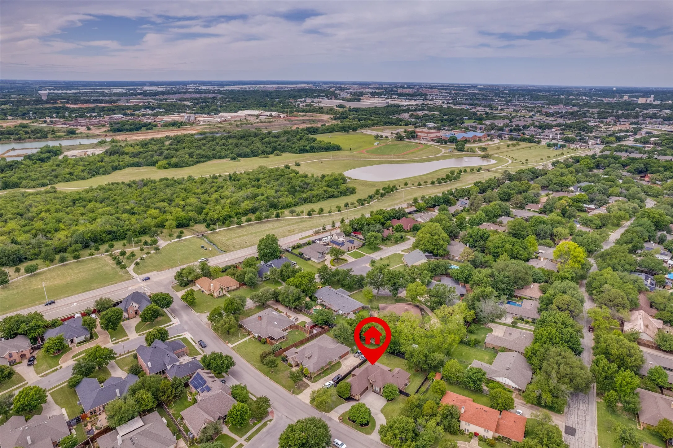 Aerial perspective highlighting a residential neighborhood with mature trees, green spaces, and a nearby body of water