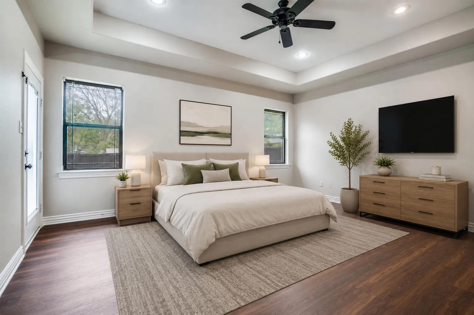 Virtual Staging Spacious primary bedroom featuring wood-finish flooring, a tray ceiling with recessed lighting, and a black ceiling fan
