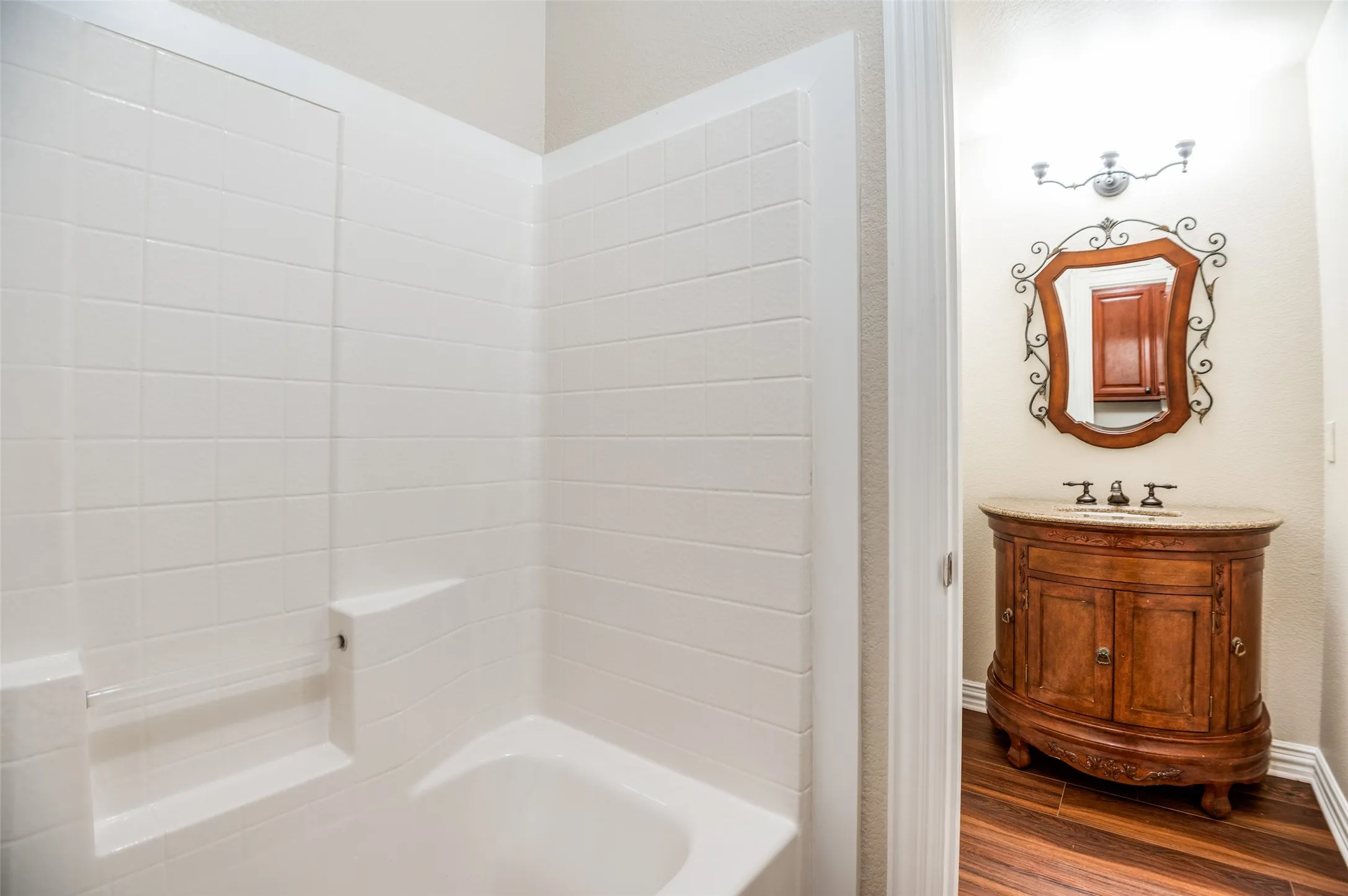 Bathroom featuring a classic white subway tile shower surround and a separate vanity area