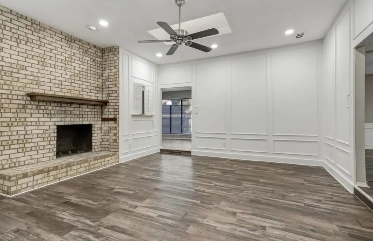Unfurnished living room with a decorative wall, ceiling fan, a brick fireplace, dark wood-style flooring, and recessed lighting