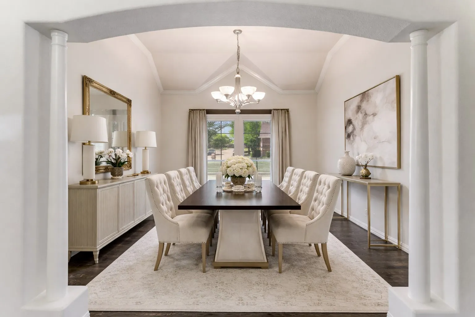 Virtually staged large Dining room with ornate columns, lofted ceiling, crown molding, suspended lighting, and dark wood finished floors