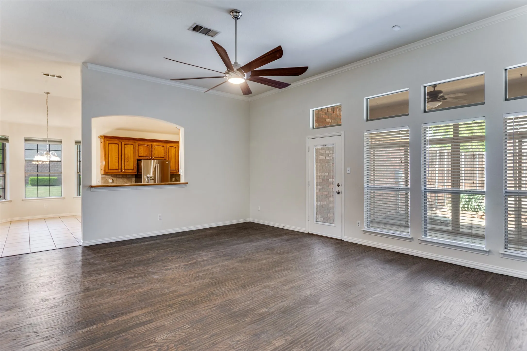 Open Concept living room with ceiling fan, ornamental molding, a high ceiling, and dark wood finished floors