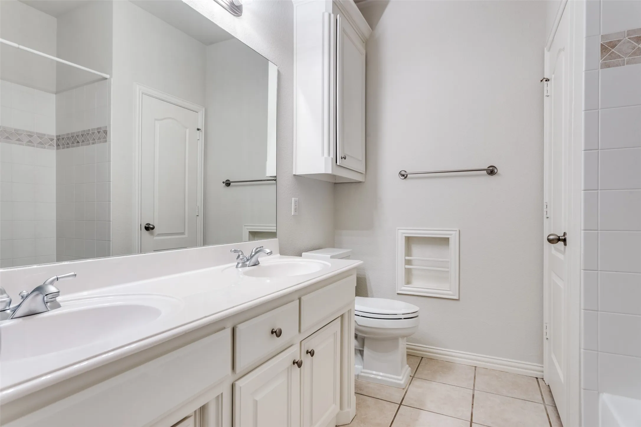 Full bath with double vanity, light tile patterned floors, and a shower-tub combination