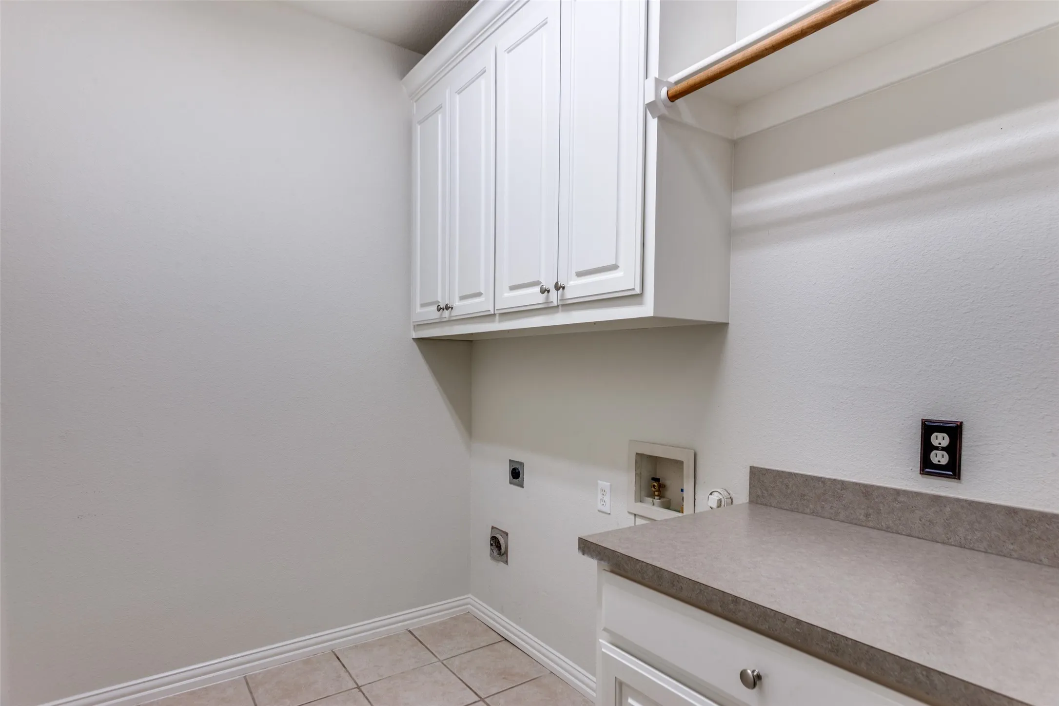 Laundry area featuring hookup for an electric dryer, hookup for a washing machine, cabinet space, and light tile patterned floors