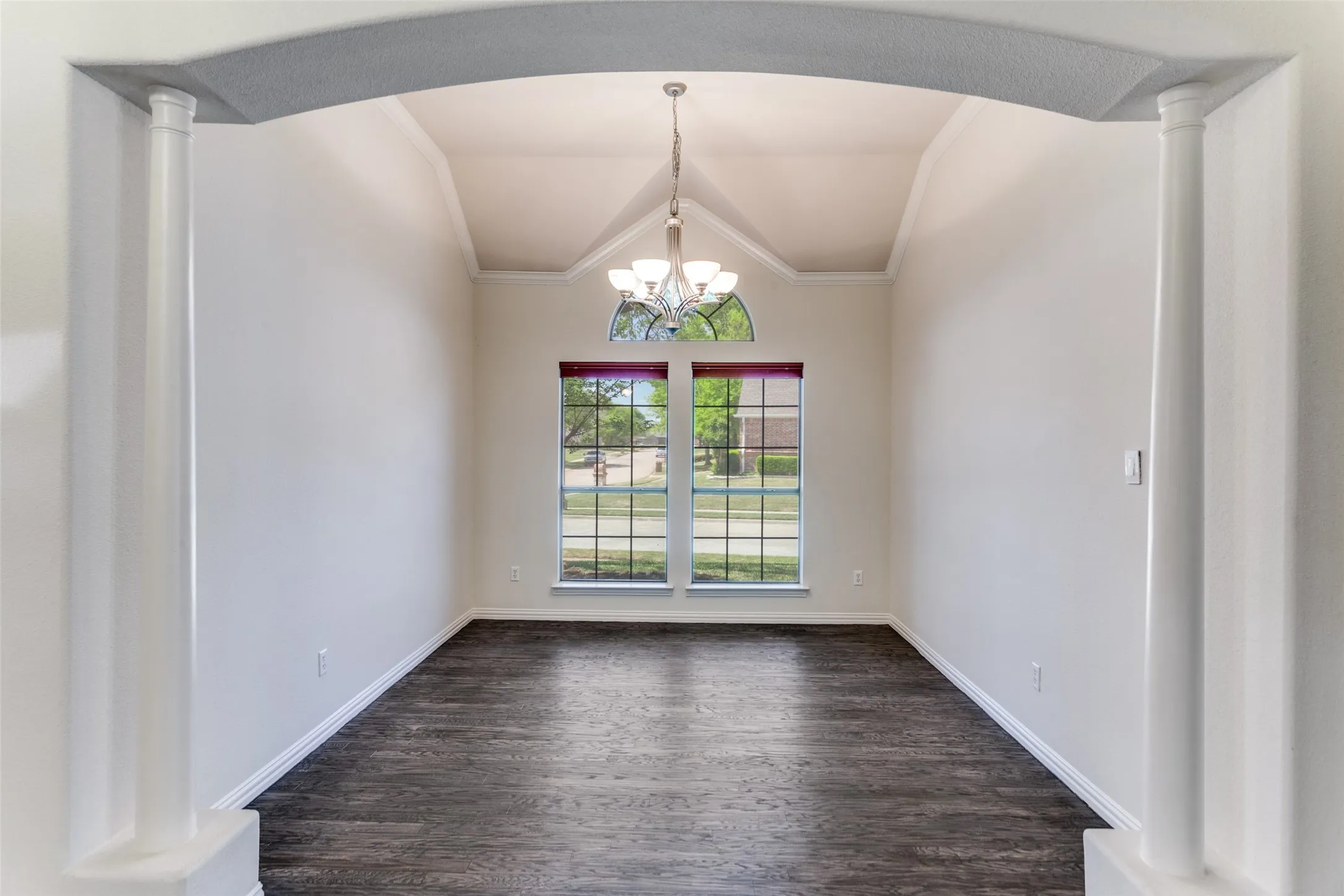 dining area featuring decorative columns, lofted ceiling, arched walkways, suspended lighting, and ornamental molding