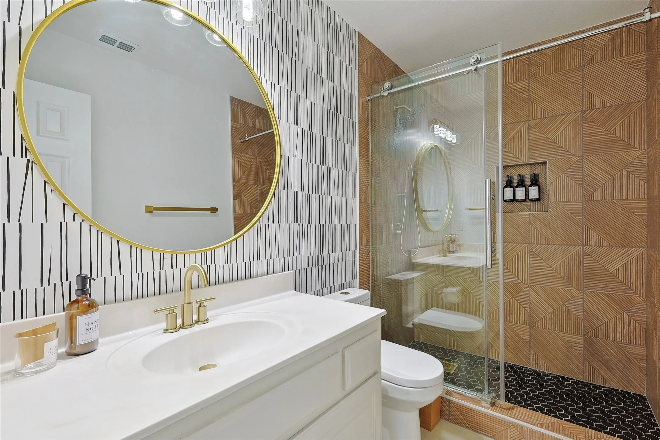 Bathroom with tile walls, backsplash, vanity with extensive cabinet space, toilet, and a shower with shower door