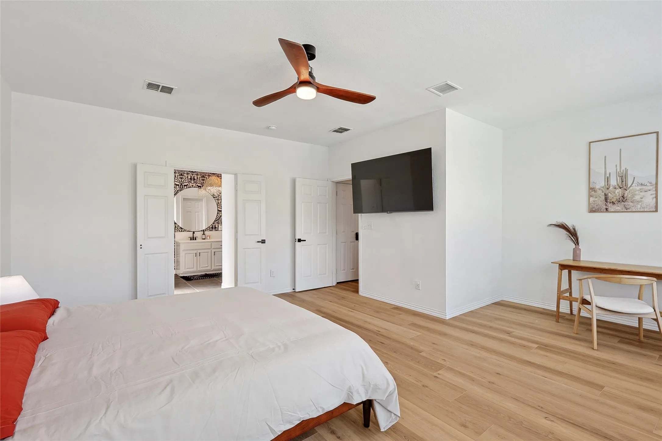 Bedroom with ceiling fan, ensuite bath, and light hardwood / wood-style flooring