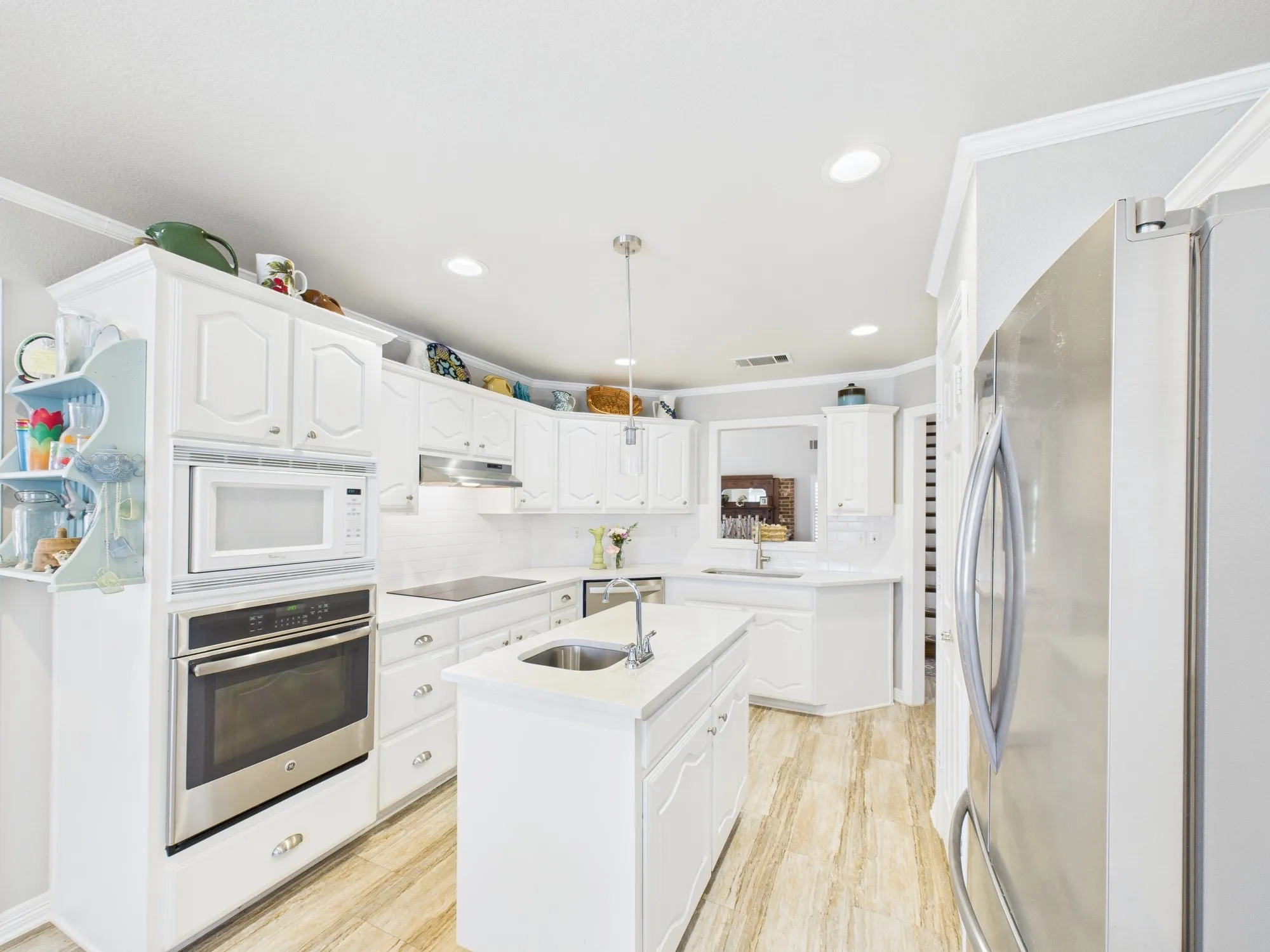 White kitchen with built-in appliances, island with water to rinse vegetables before cooking