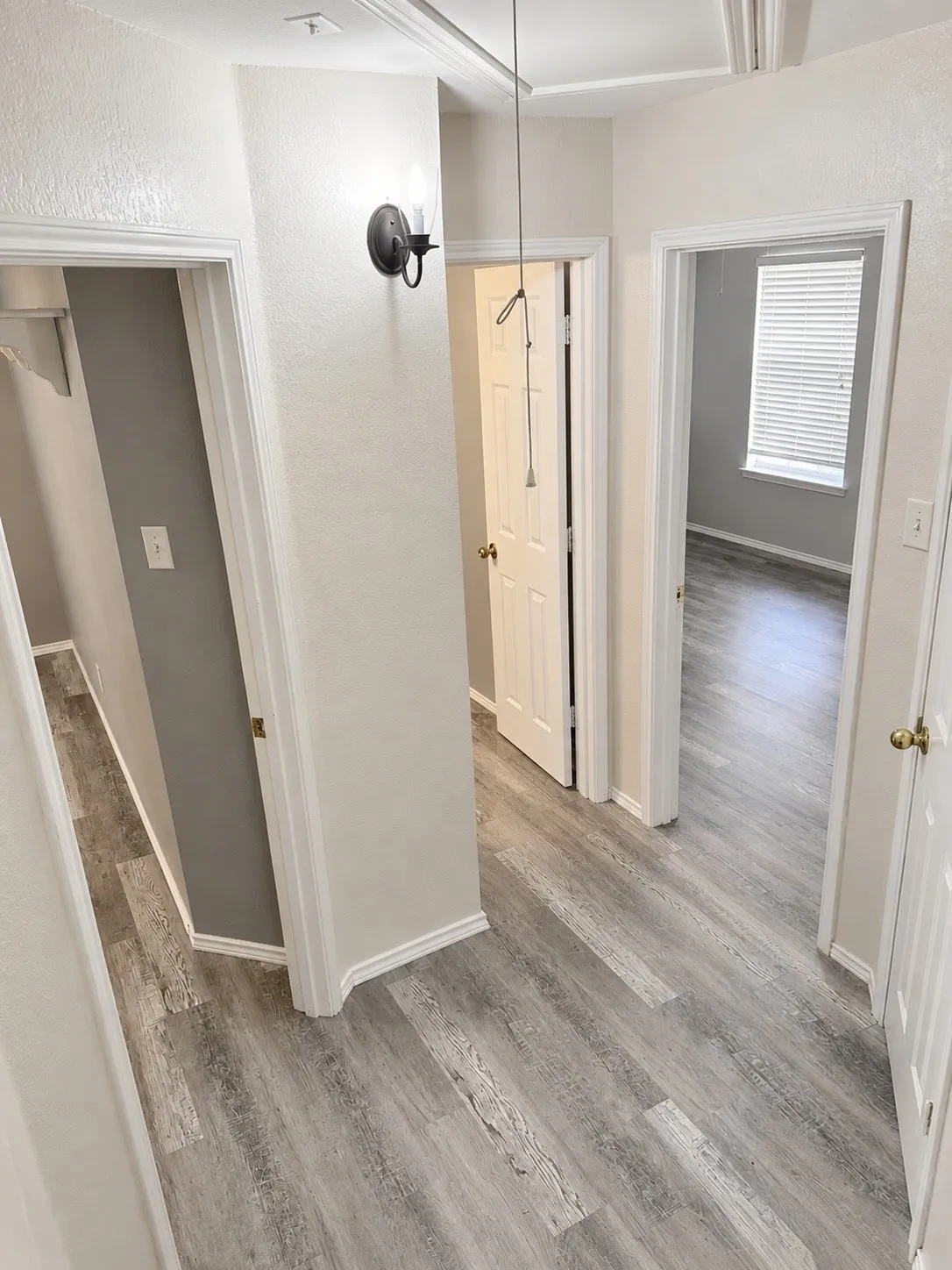 Hallway featuring wood-finish flooring, white baseboards, and neutral wall paint